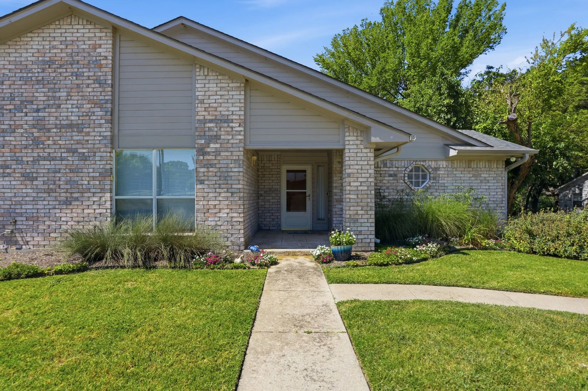 Brick exterior with siding accents, gabled roofline, front entry porch, and a circular window detail