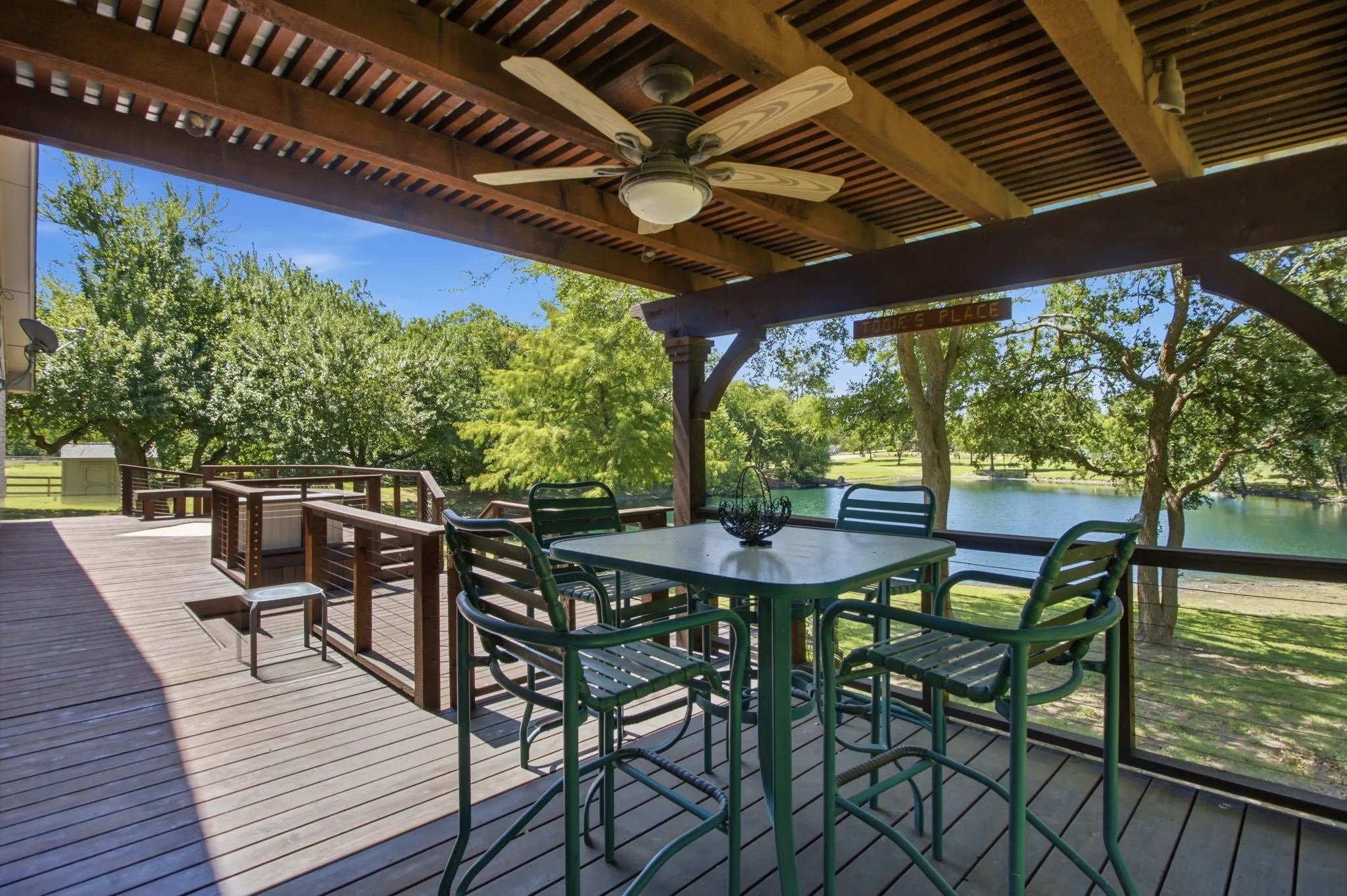 Deck with pergola and views of a serene pond with mature trees.
