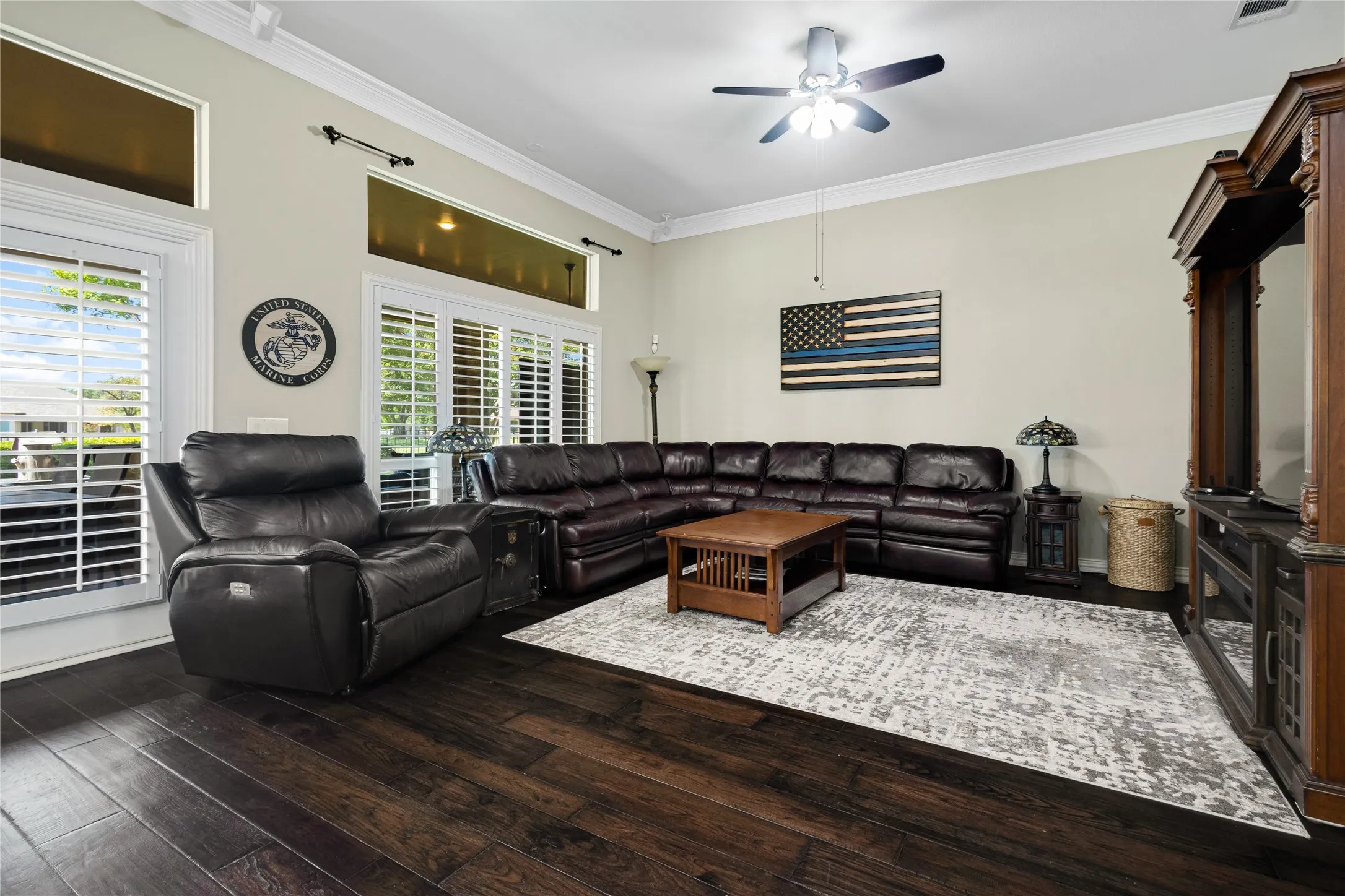 Dark wood-finish flooring, crown molding, and multiple windows with plantation shutters
