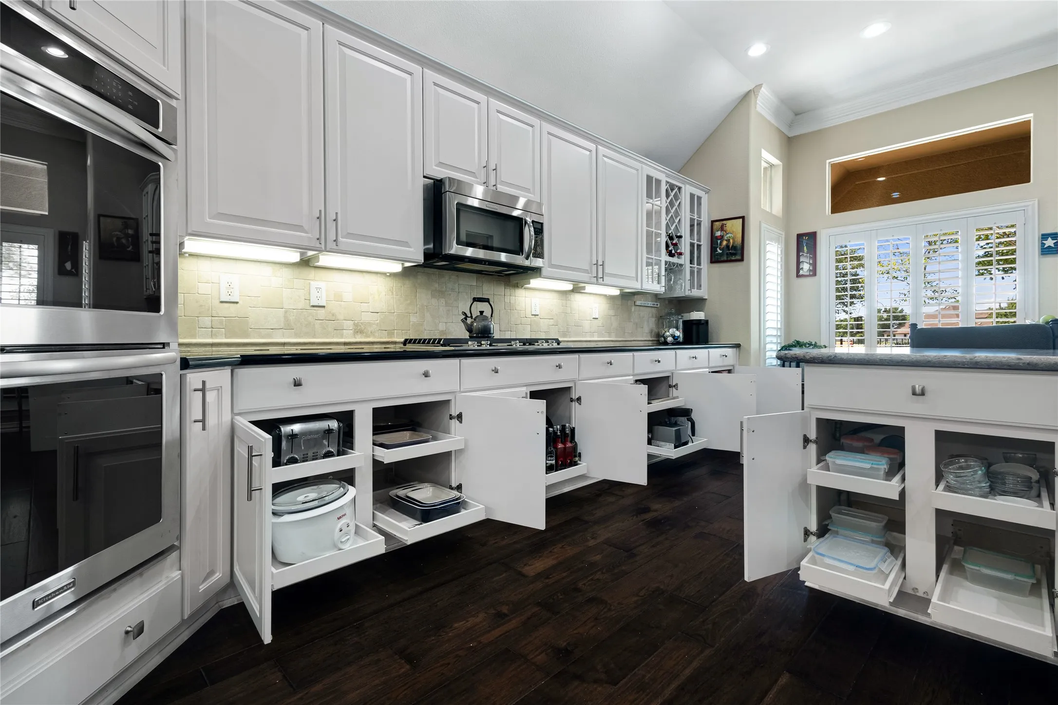 Kitchen featuring white cabinetry with brushed nickel hardware, stainless steel appliances, dark wood-finish flooring, and a subway tile backsplash
