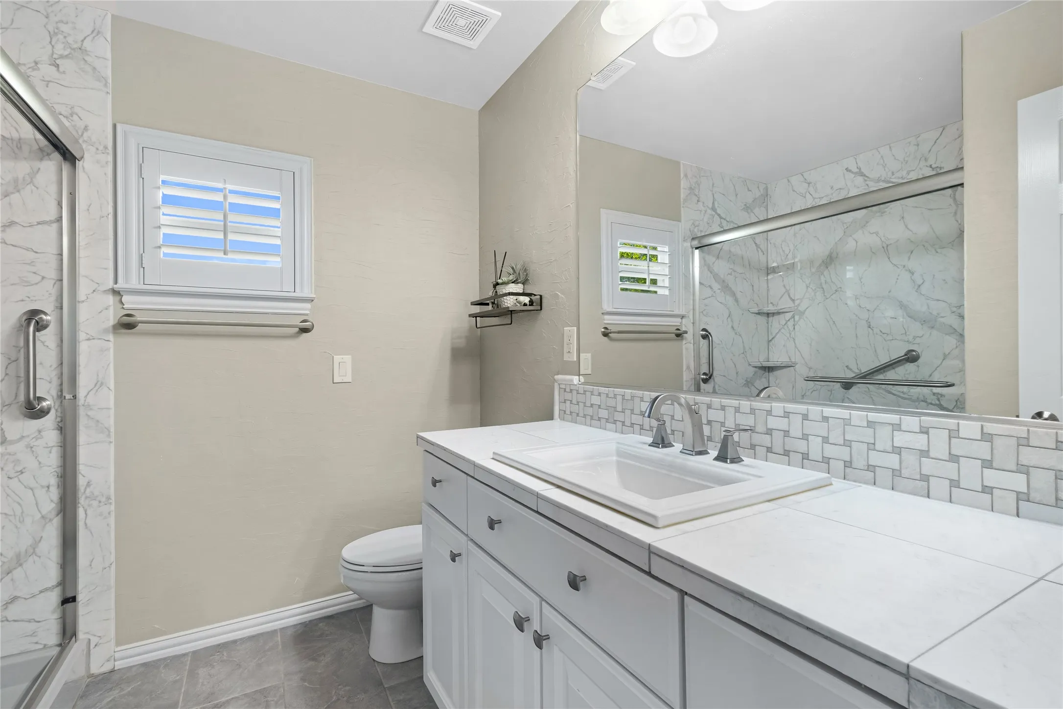 White shaker-style vanity with an integrated sink, white countertop, and mosaic tile backsplash