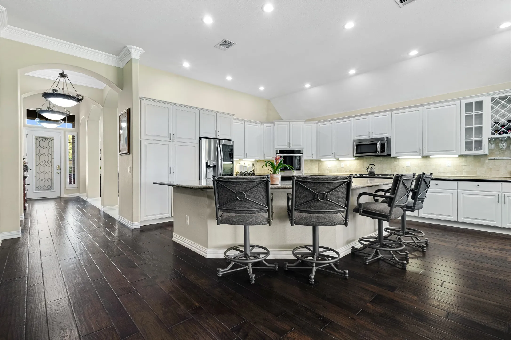 Kitchen featuring white cabinetry, stainless steel appliances, an island with countertop seating, recessed lighting, and wood-finish flooring