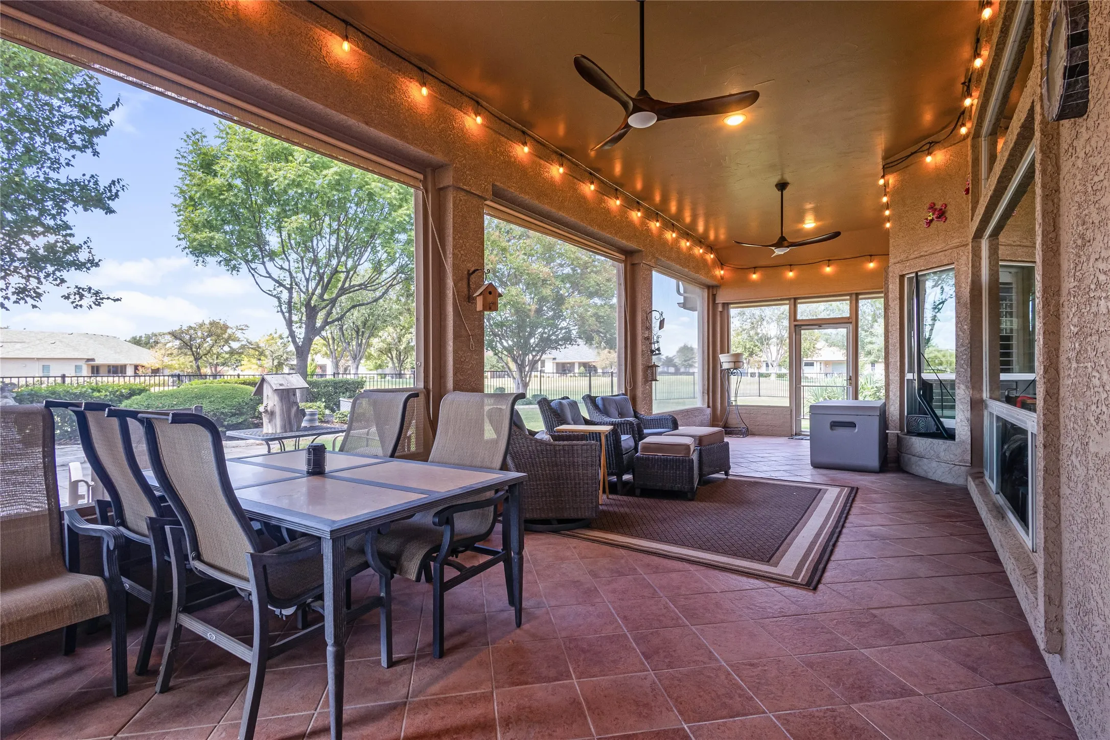 Spacious covered patio featuring durable tile flooring, multiple ceiling fans, recessed lighting, and large windows