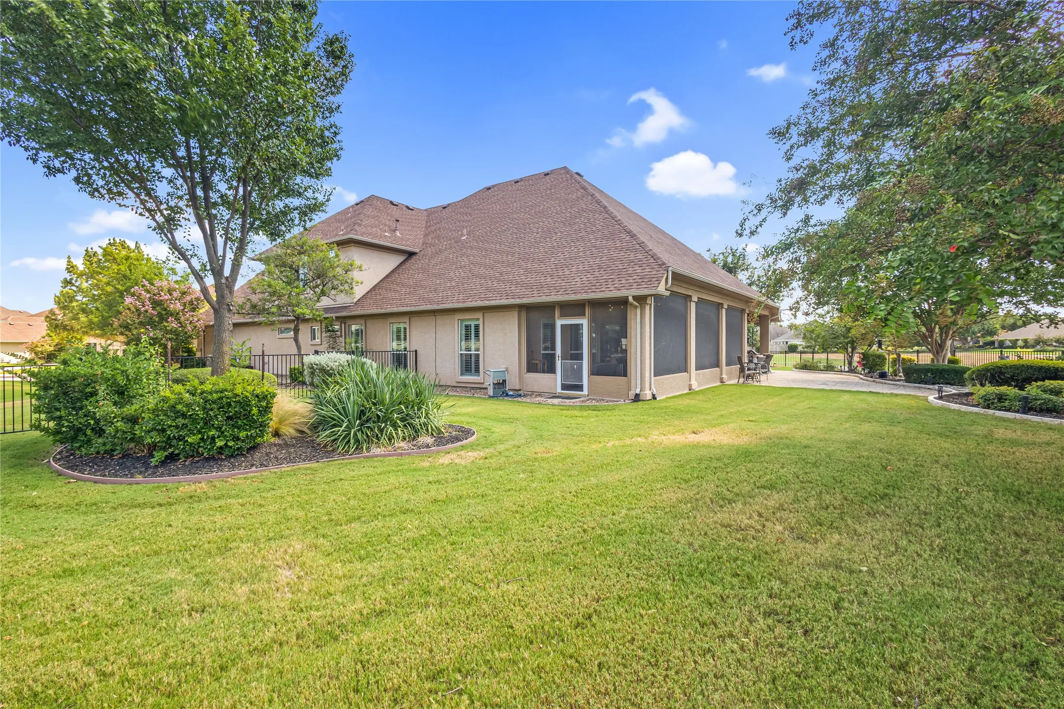 Expansive yard with mature trees, established landscaping, and a screened-in porch