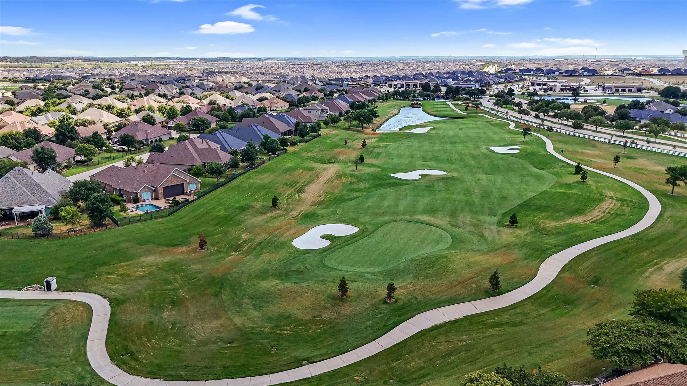 Expansive golf course setting featuring manicured greens, sand traps, and a water feature