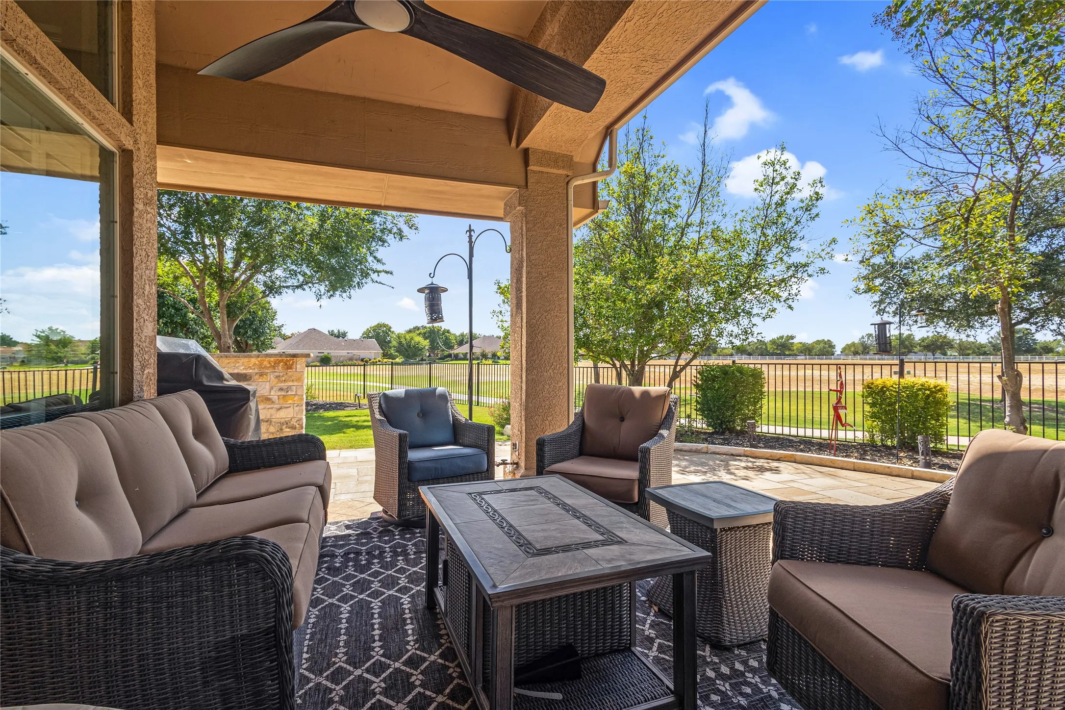 Expansive covered patio featuring a ceiling fan, stone-accented outdoor kitchen, and paver patio flooring