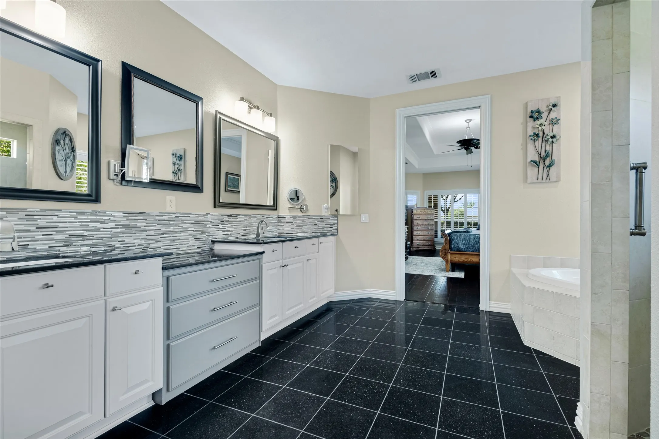 Dual vanity with white cabinetry, a gray drawer bank, and dark countertops
