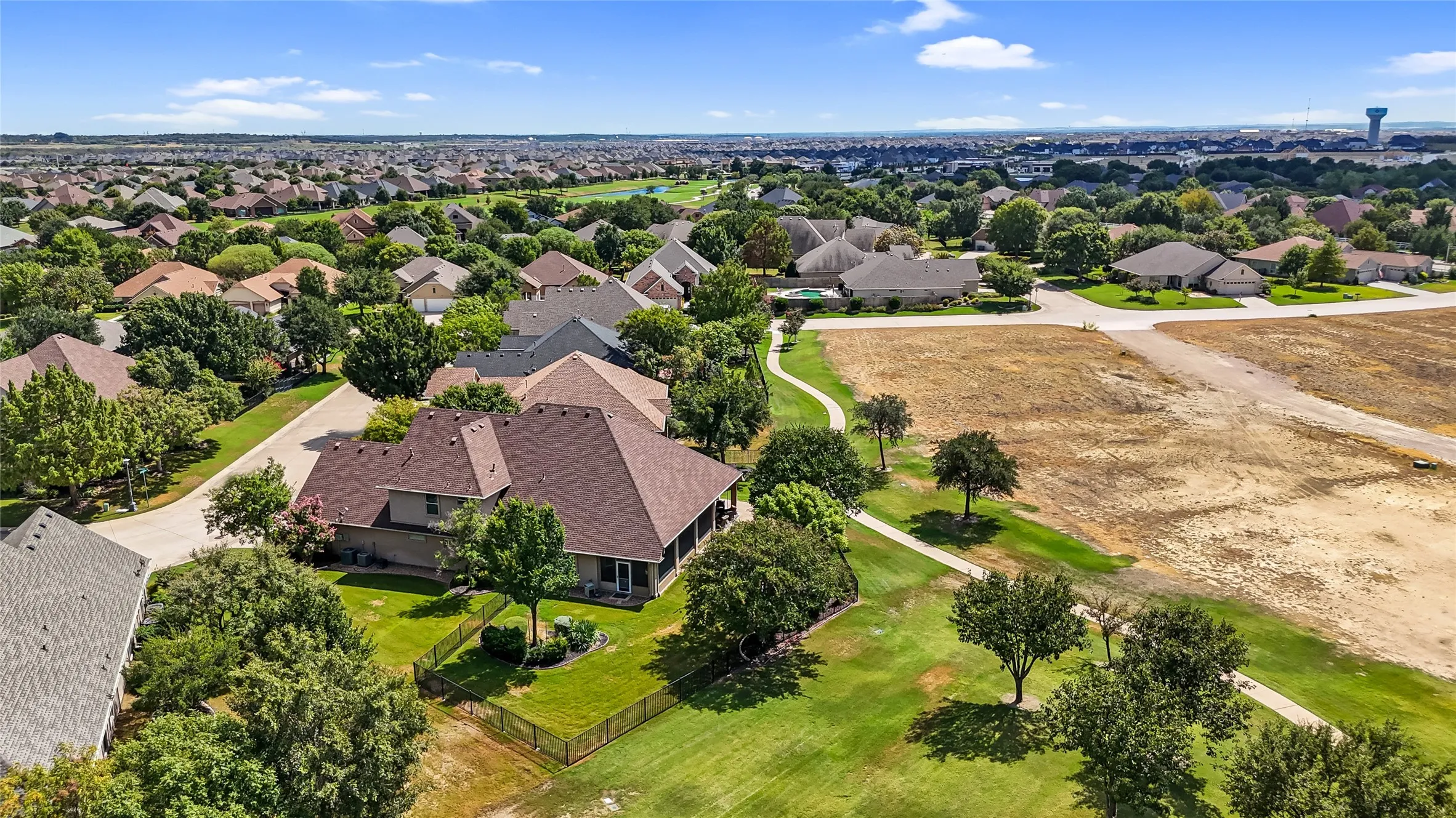 Expansive property featuring a large residence with a screened porch, a sizable lawn area, and mature trees