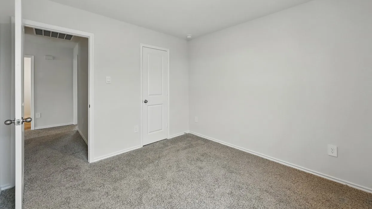 Room featuring light gray wall paint, gray carpeting, white baseboards, and a white interior door with a silver-tone knob