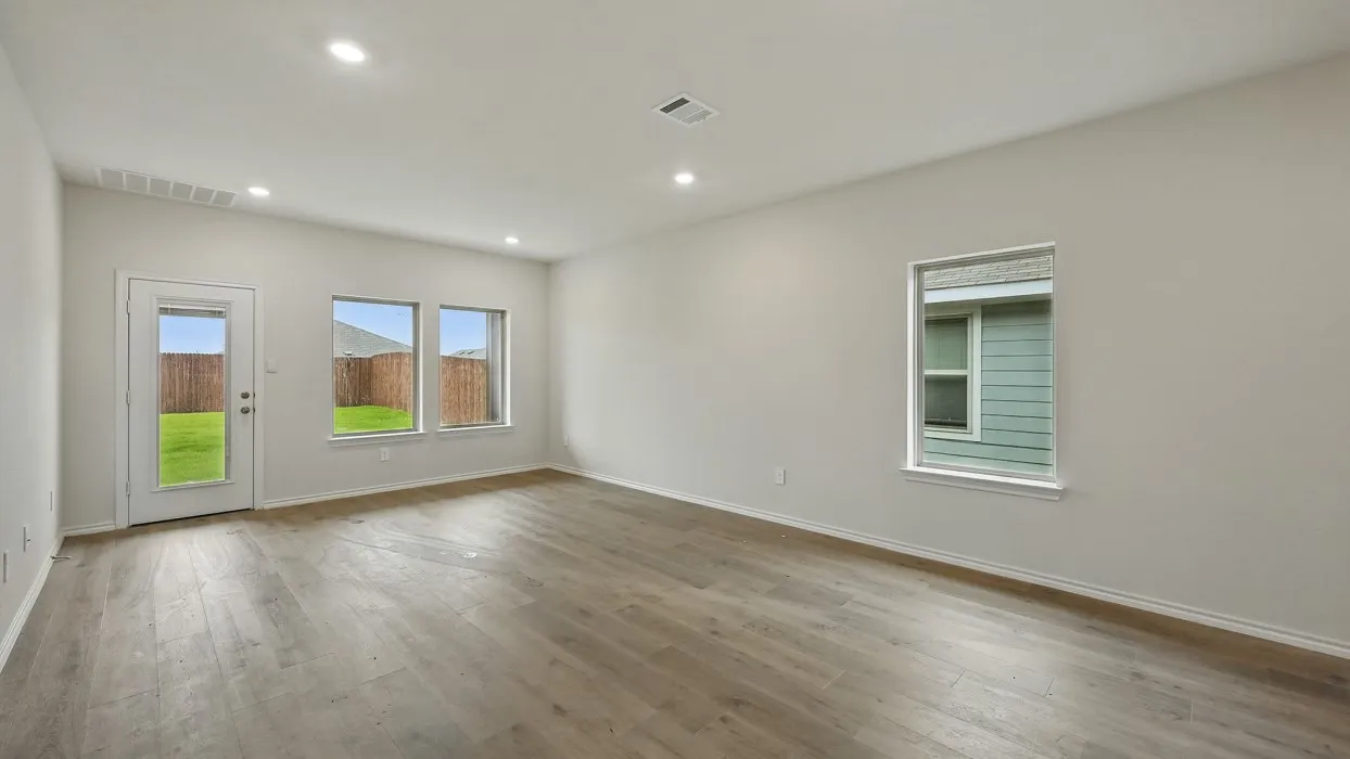 Spacious room with wood-finish flooring, recessed lighting, and ample natural light from multiple windows