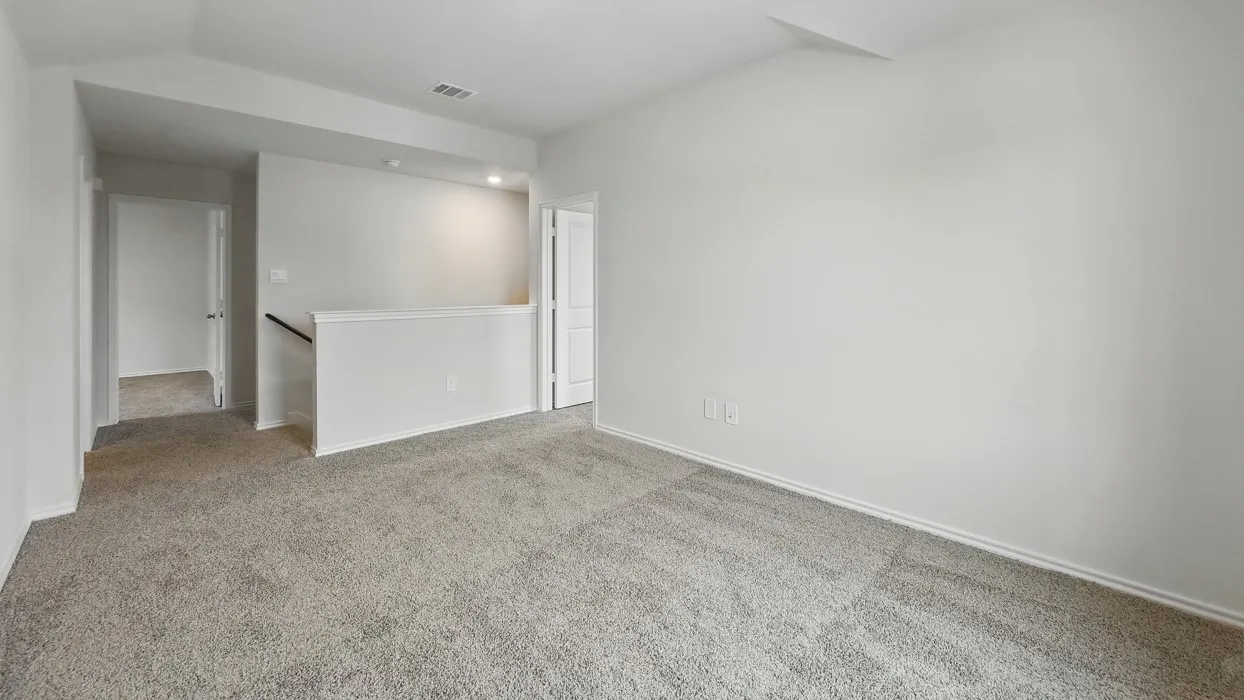 Expansive carpeted room featuring light gray walls, white baseboards, and overhead recessed lighting