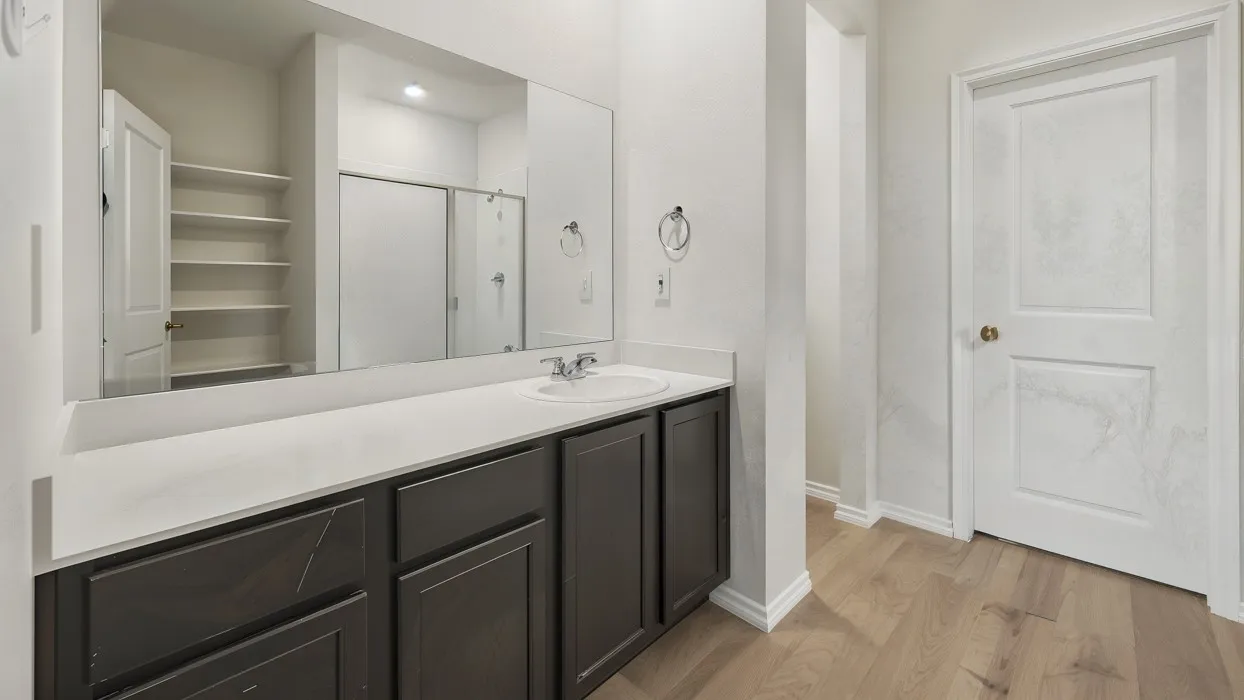 Contemporary bathroom vanity with a single sink, light-colored countertop, and dark wood-finish cabinetry