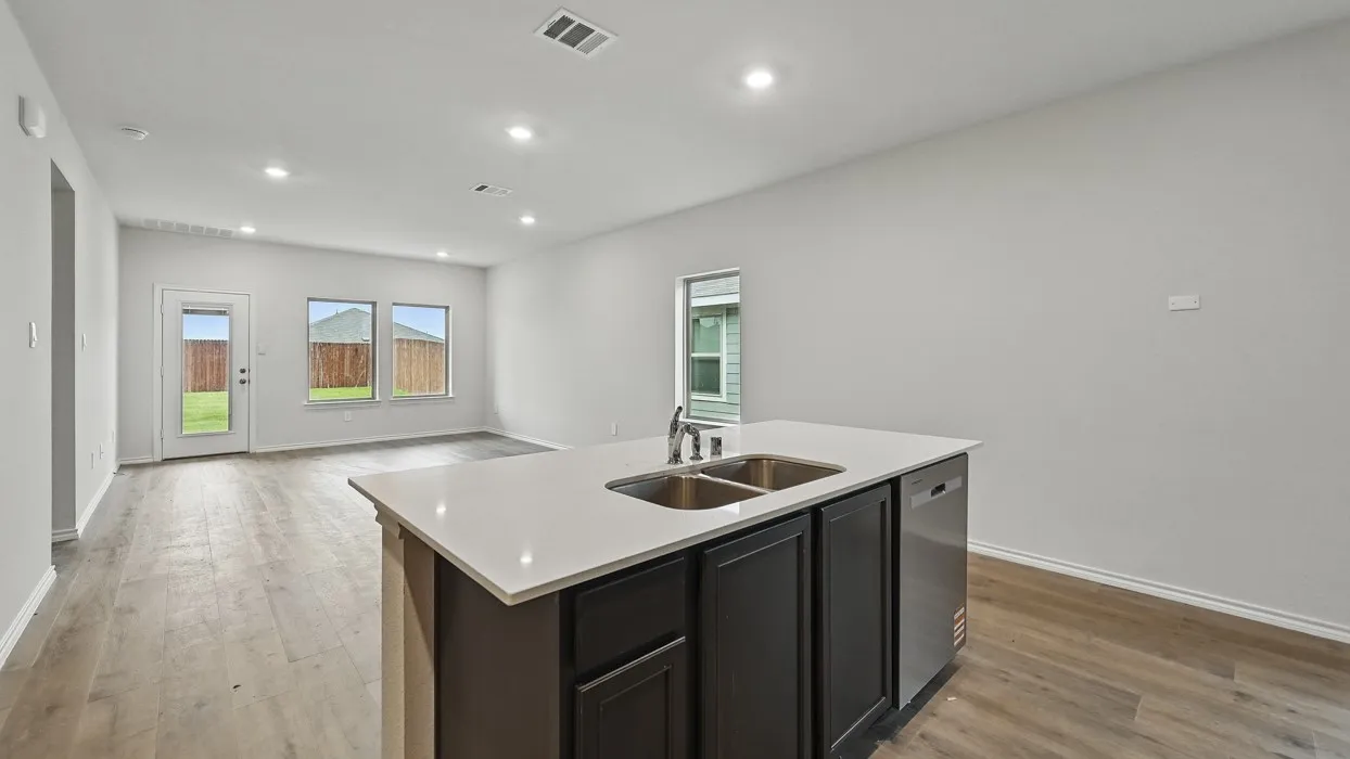 Kitchen island with an undermount double-basin stainless steel sink, a stainless steel dishwasher, and a light-toned countertop