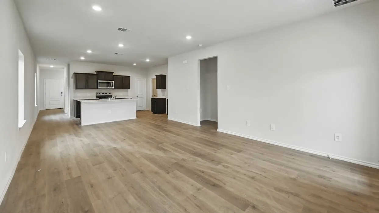 Spacious open-concept living area featuring wood-finish flooring, recessed lighting, and white walls