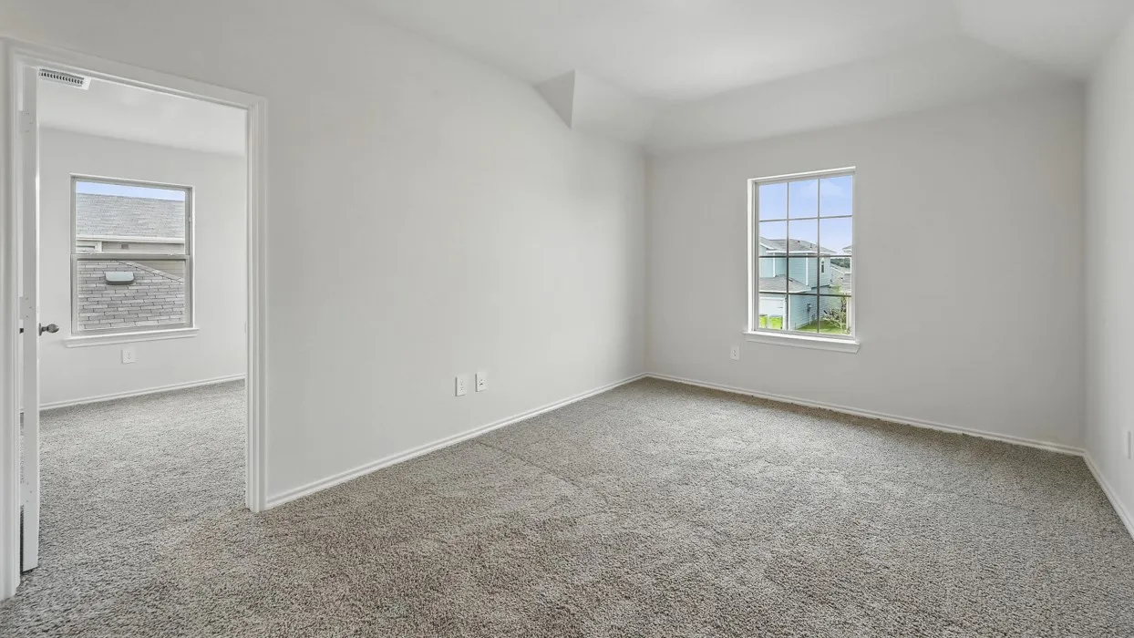 Spacious room featuring vaulted ceilings, neutral-toned walls, and plush grey carpet