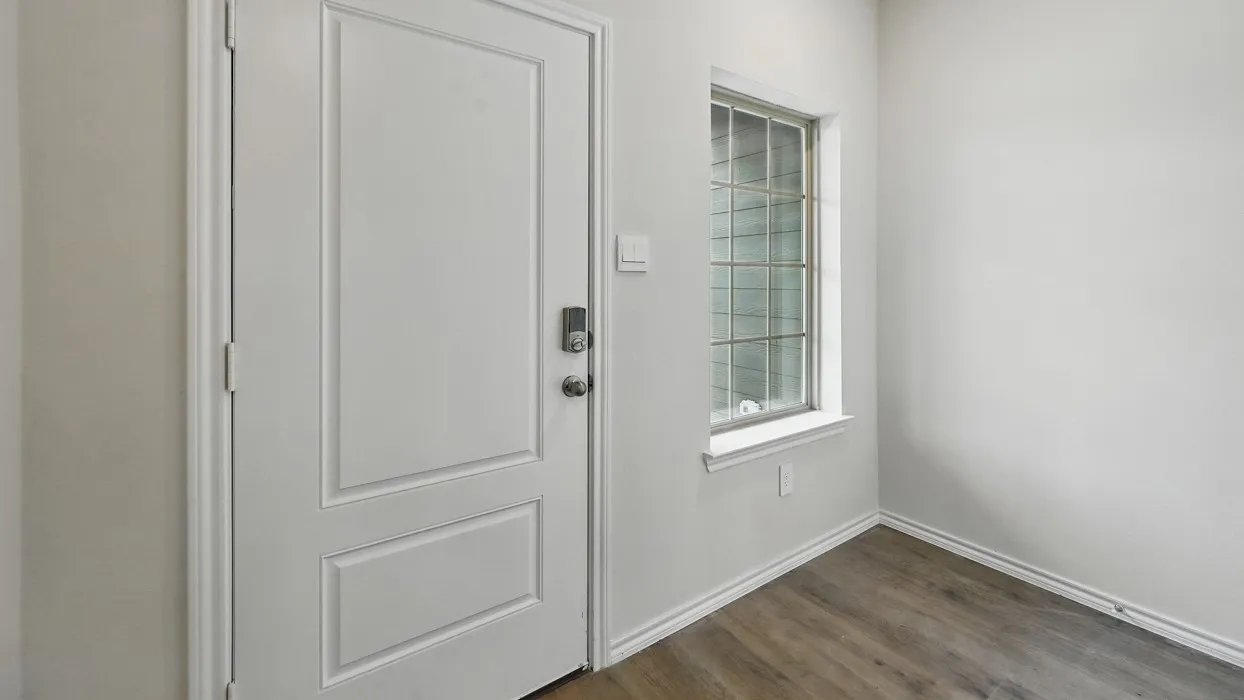 Entryway featuring a paneled door with smart lock hardware, a multi-paned window, neutral wall paint, and wood-finish flooring