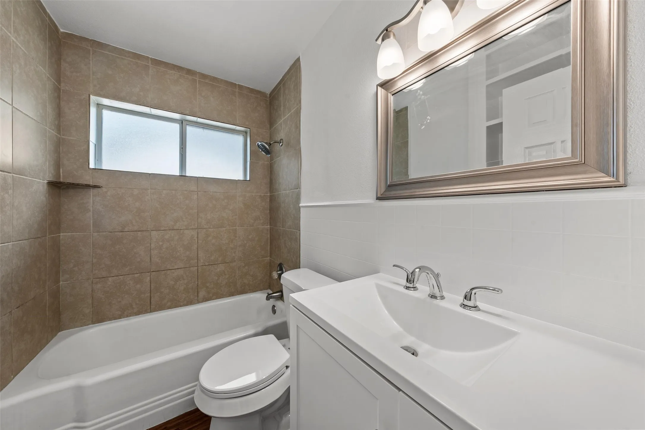 White vanity with integrated sink, chrome faucet, and framed mirror with integrated lighting