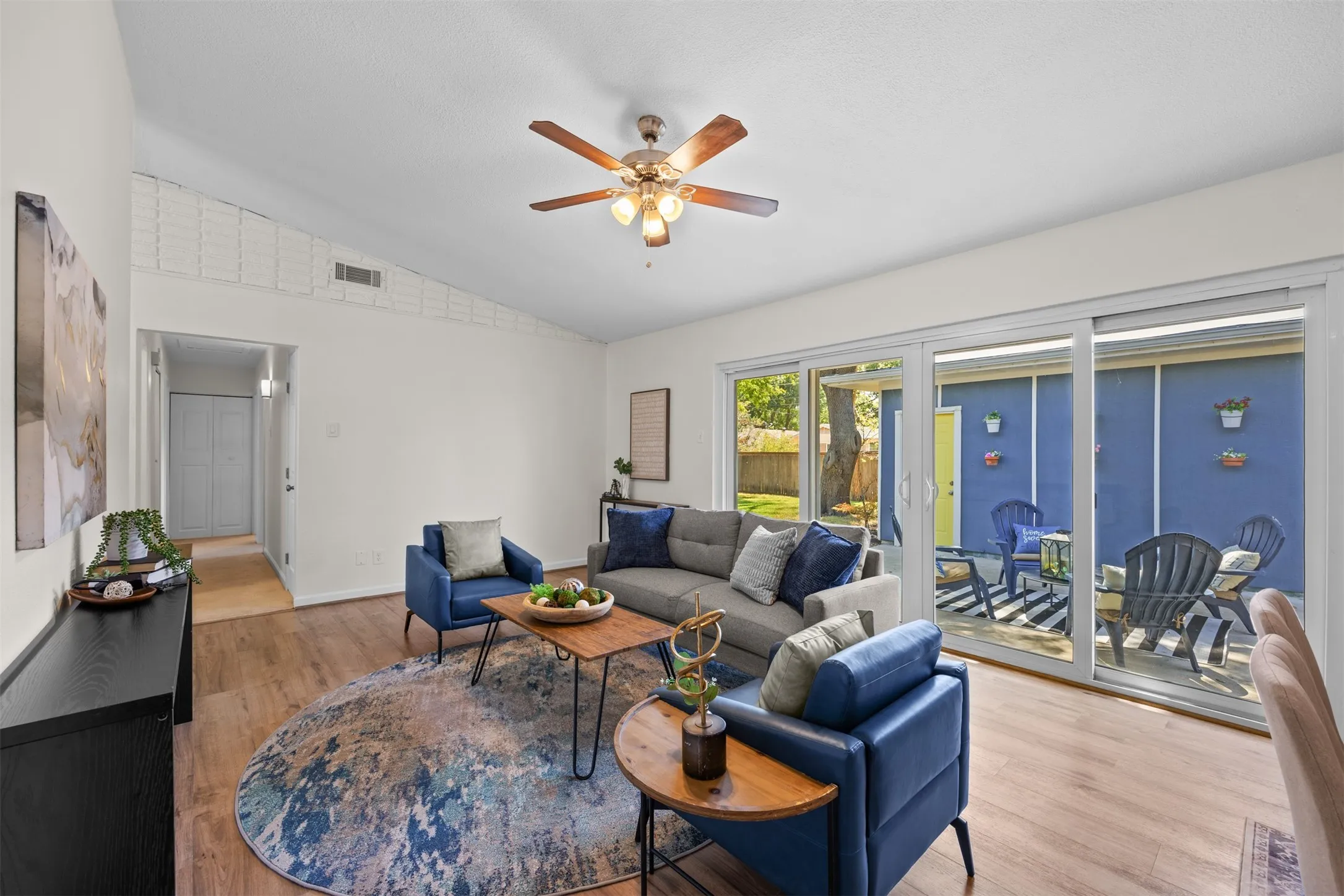 Vaulted ceiling with an overhead fan, wood-finish flooring, and sliding glass patio doors