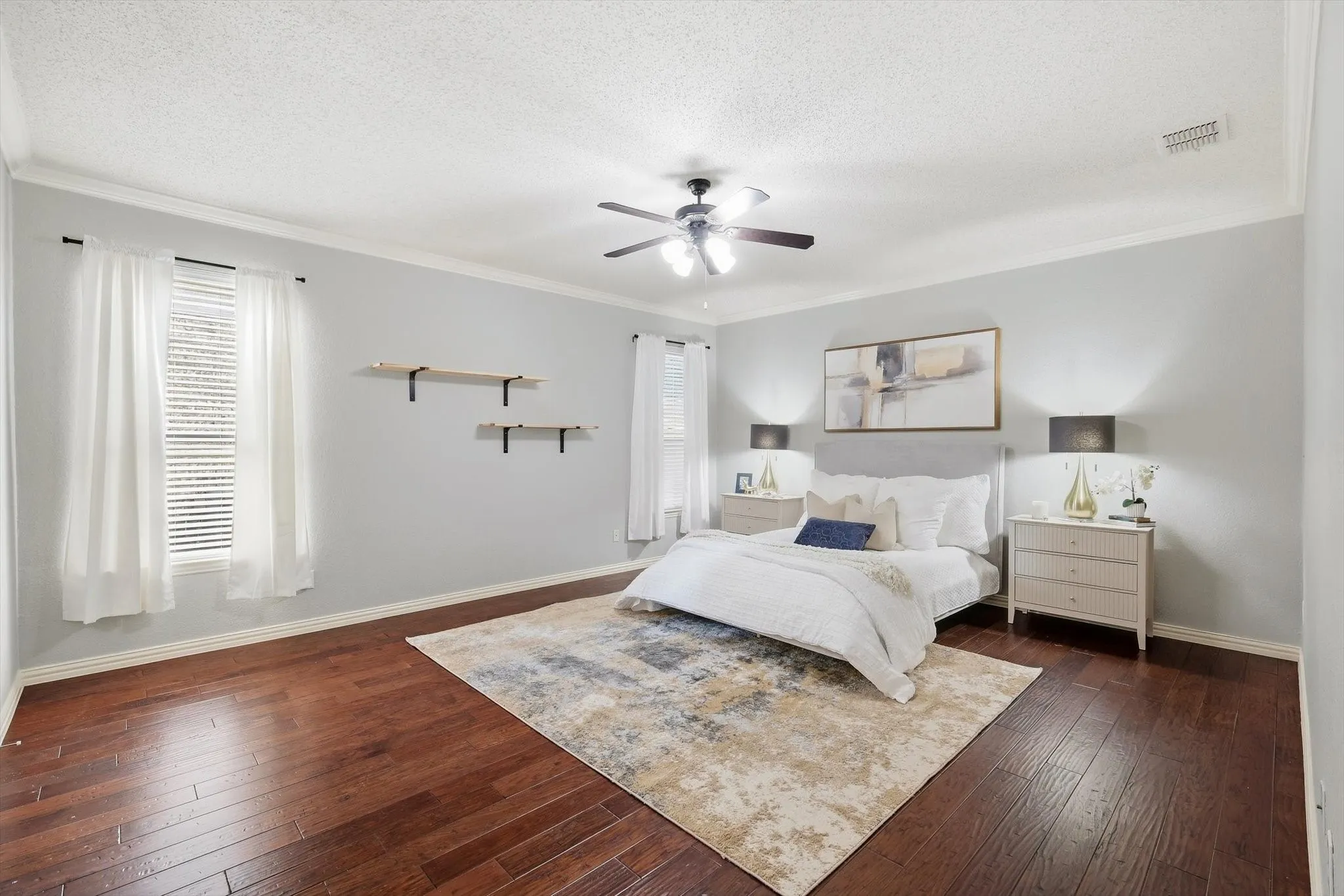 Wood-finish flooring, crown molding, ceiling fan with integrated lighting, and window treatments