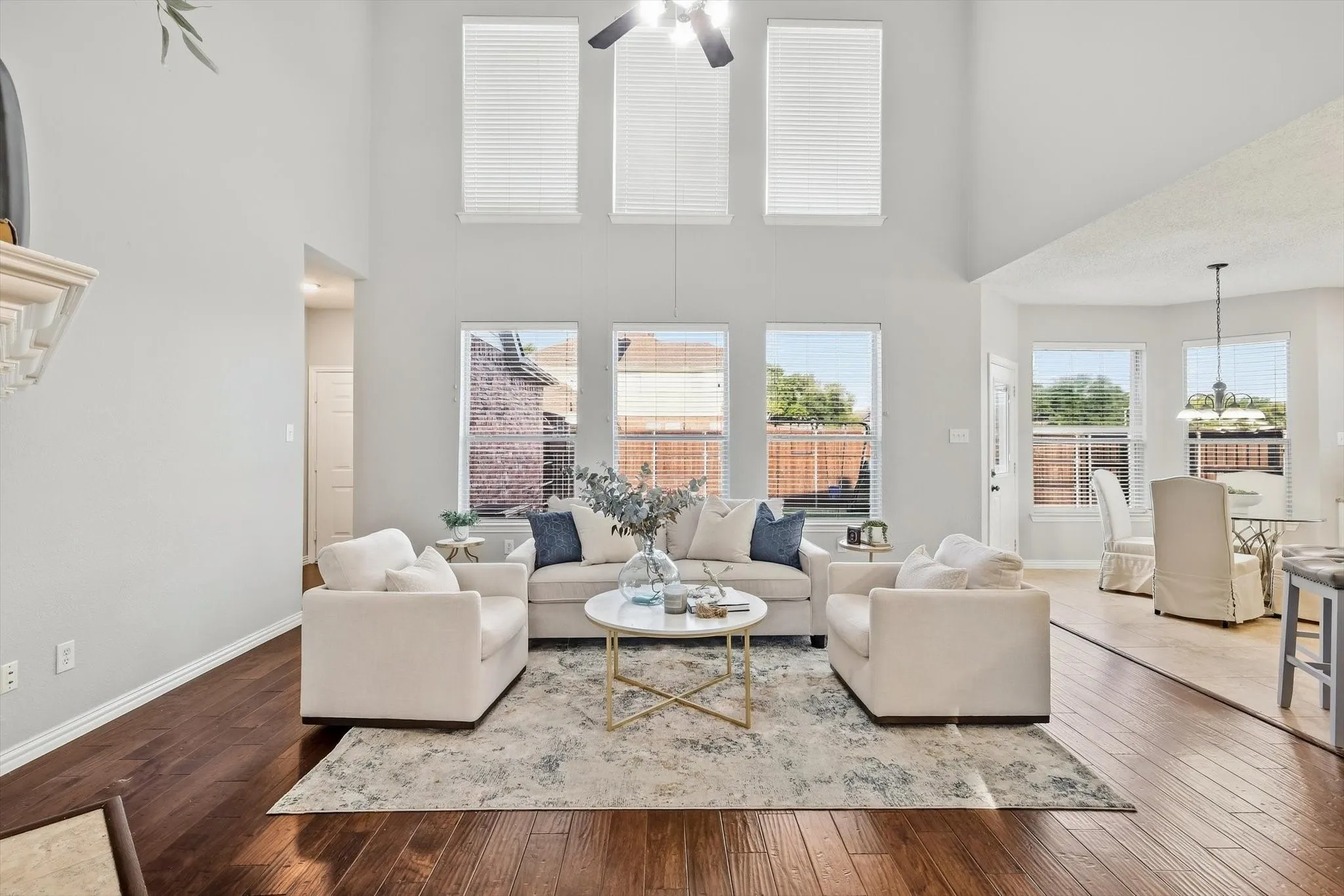 Vaulted ceiling with a ceiling fan, multiple windows with blinds, and wood-finish flooring