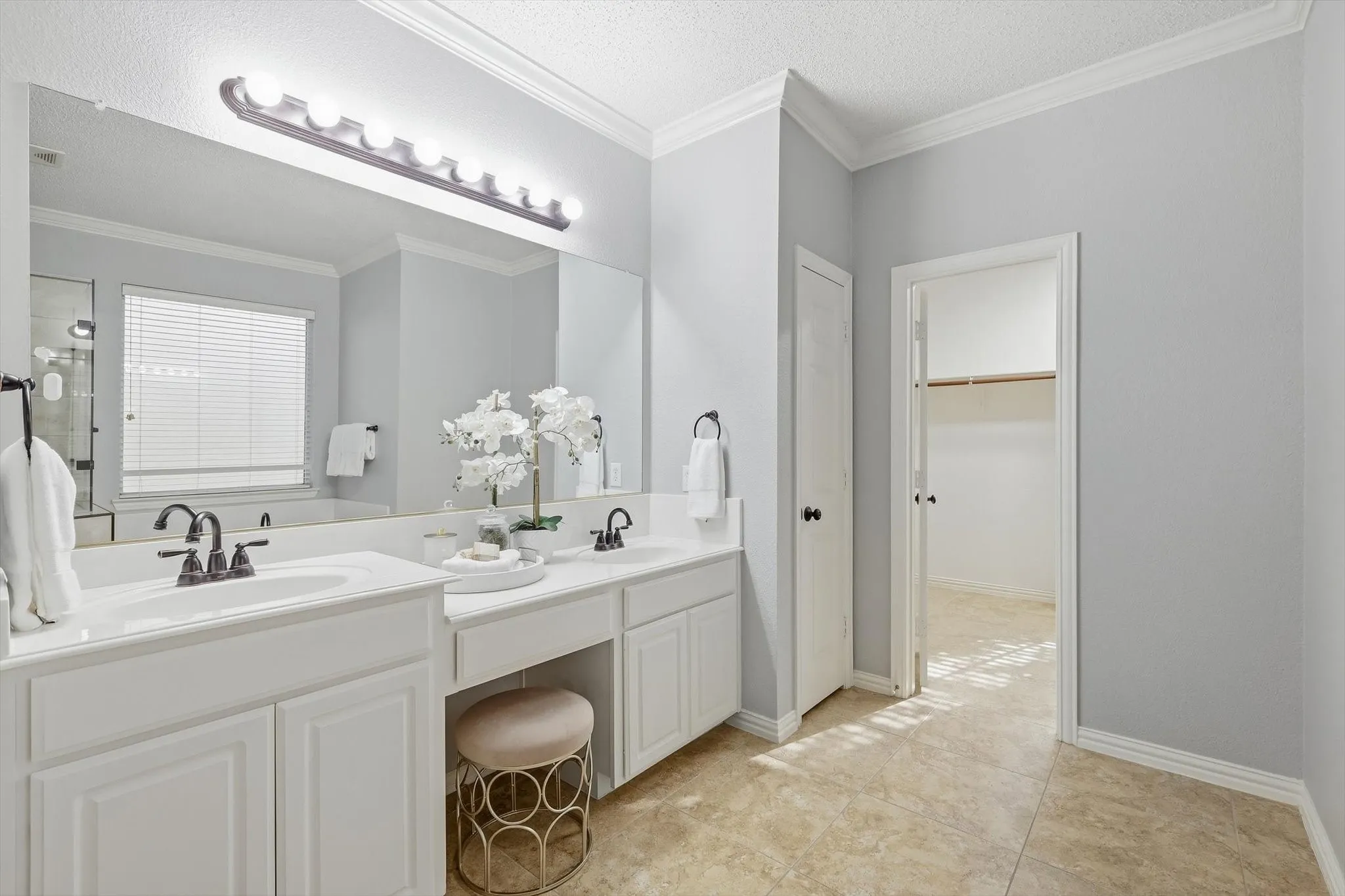 Dual vanity with white cabinetry, integrated sinks, dark bronze fixtures, and a large wall-mounted mirror