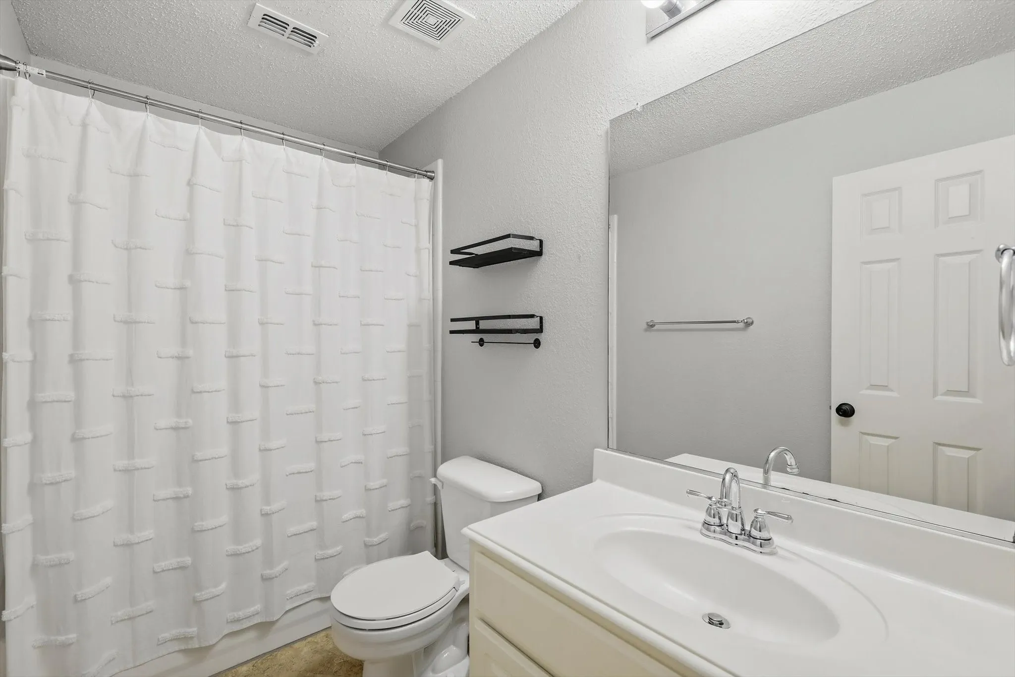 Bathroom featuring a white vanity with integrated sink, chrome faucet, and a large wall-mounted mirror