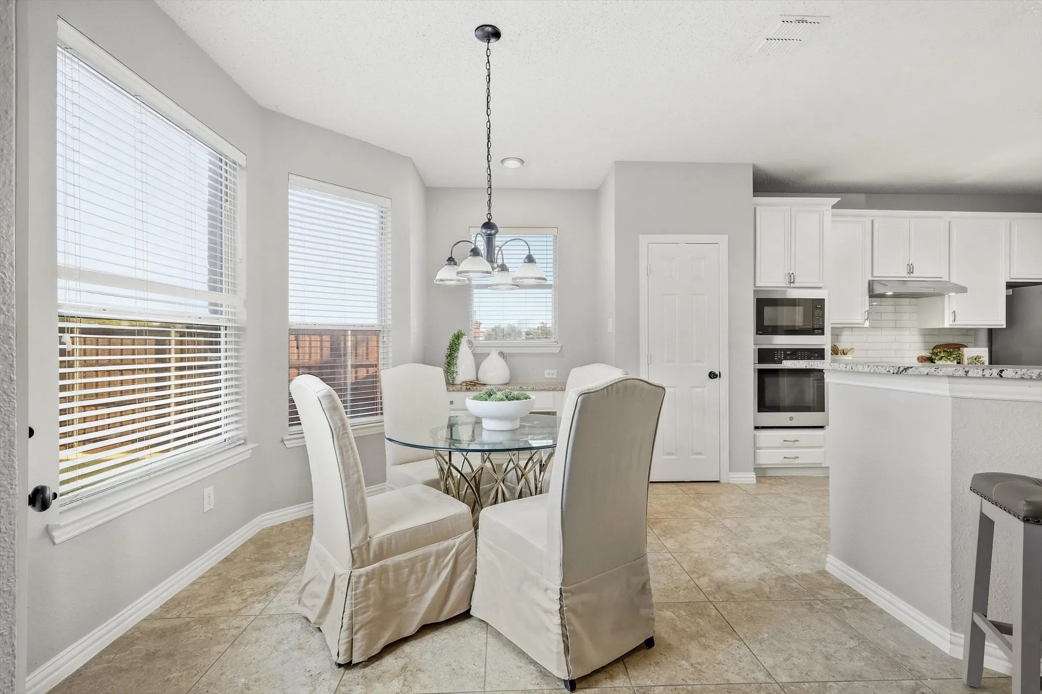 Kitchen with white cabinetry, built-in microwave and oven, and subway tile backsplash