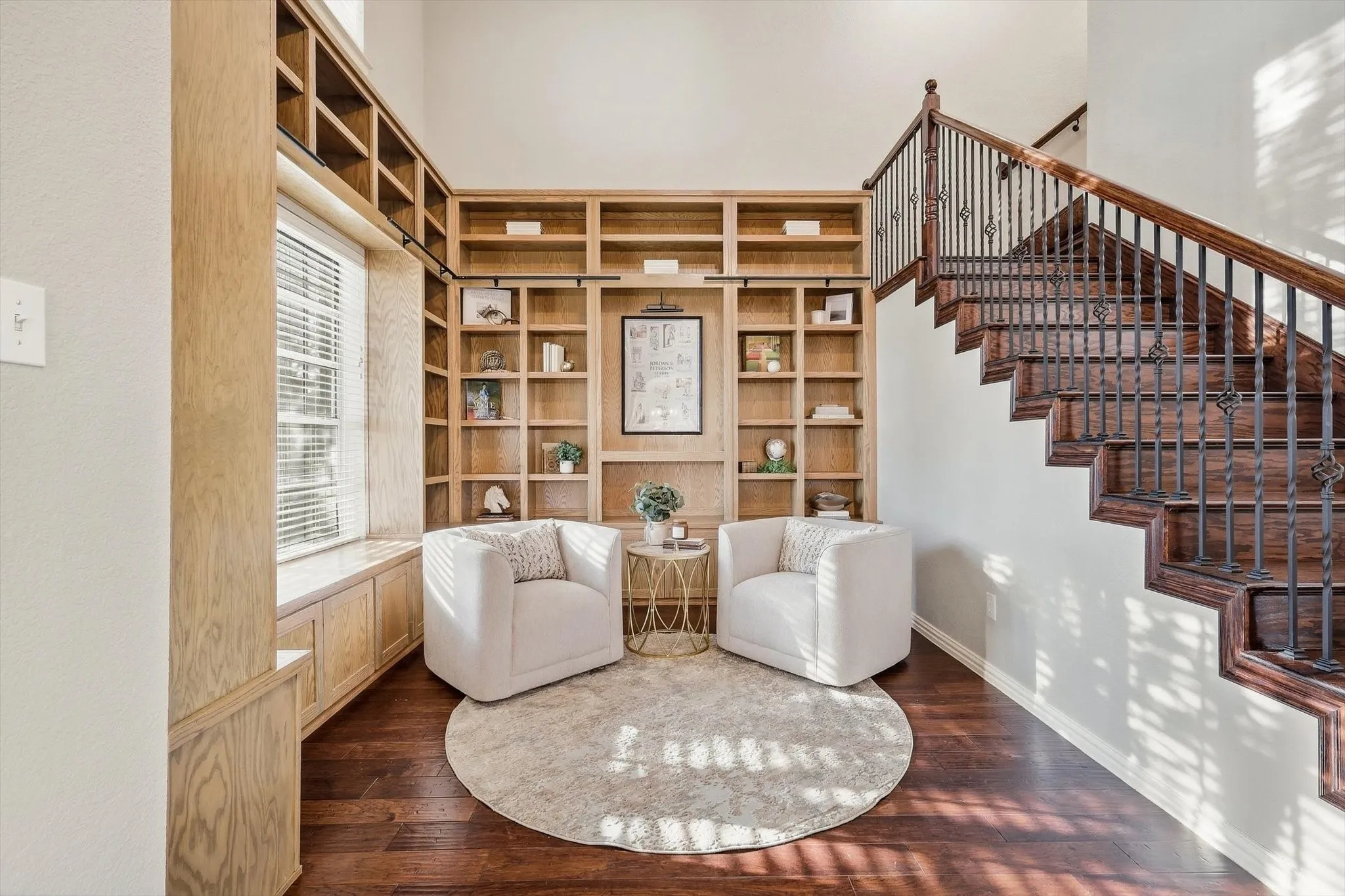 Built-in shelving with integrated lighting, wood-finish flooring, custom staircase with wrought iron balusters, and a window seat with storage cabinetry
