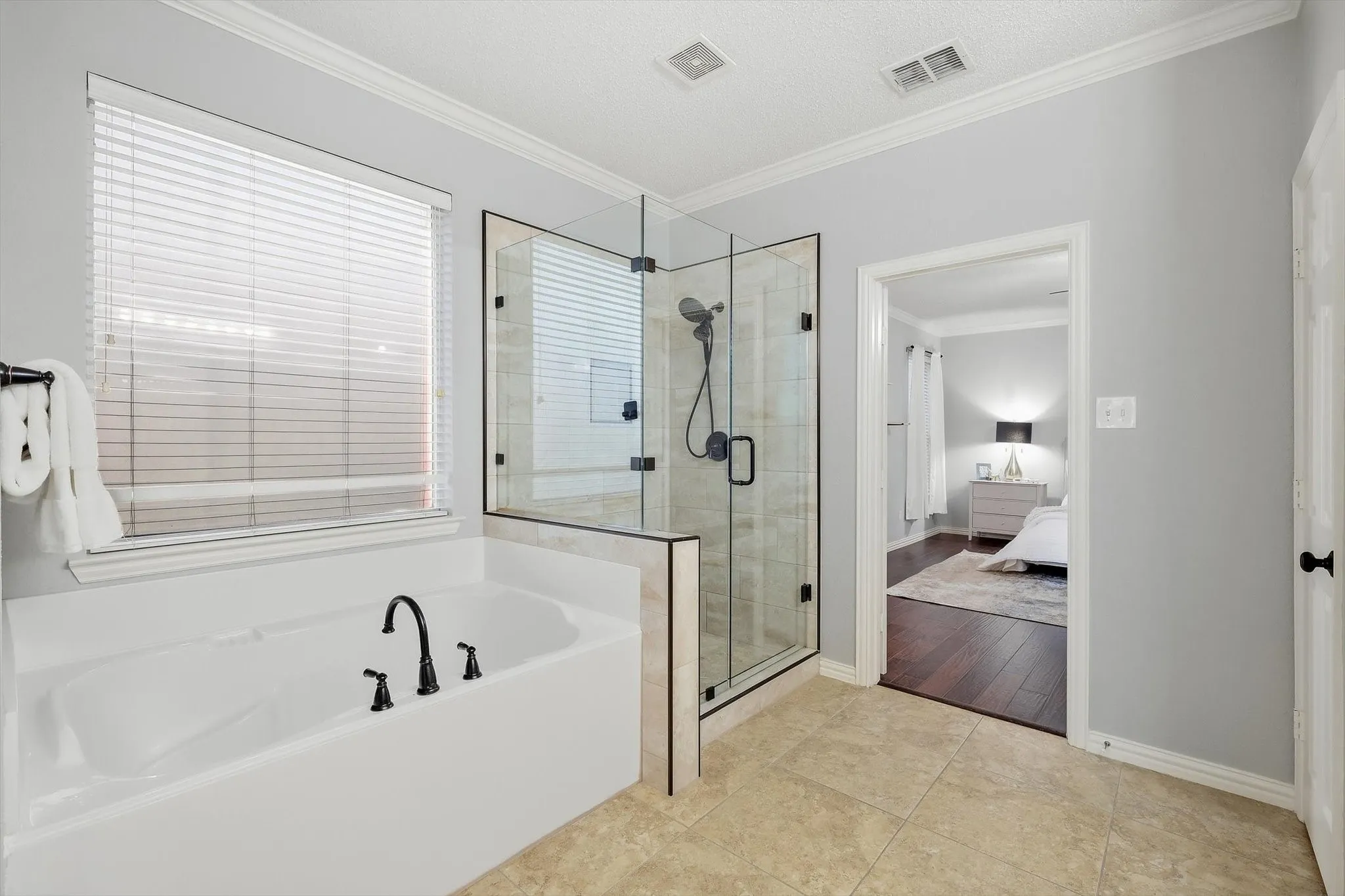 Soaking tub with matte black fixtures, glass-enclosed shower, and tile flooring