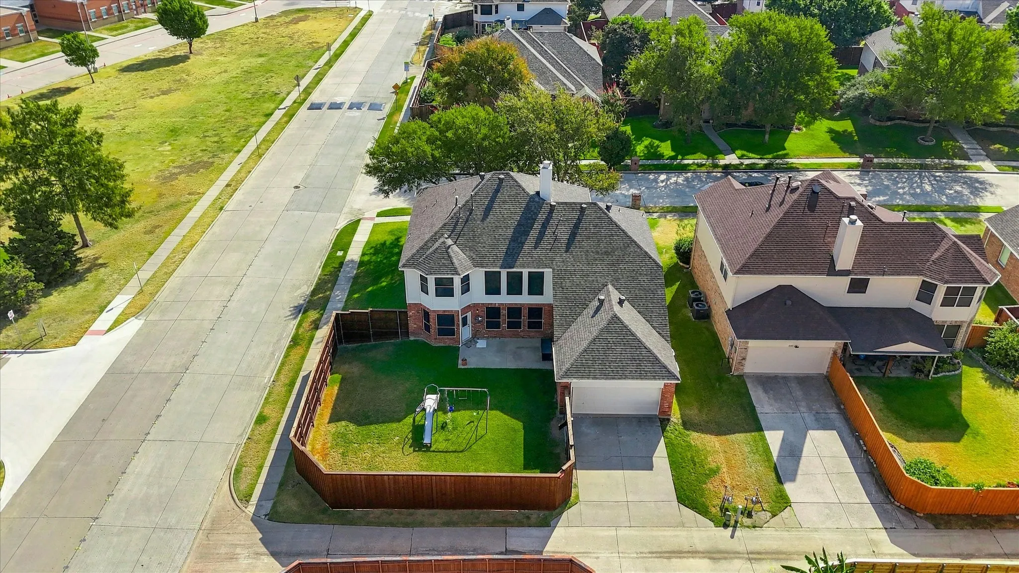 Two-story residence featuring a brick and siding exterior, multi-pane windows, and a fenced backyard with a manicured lawn
