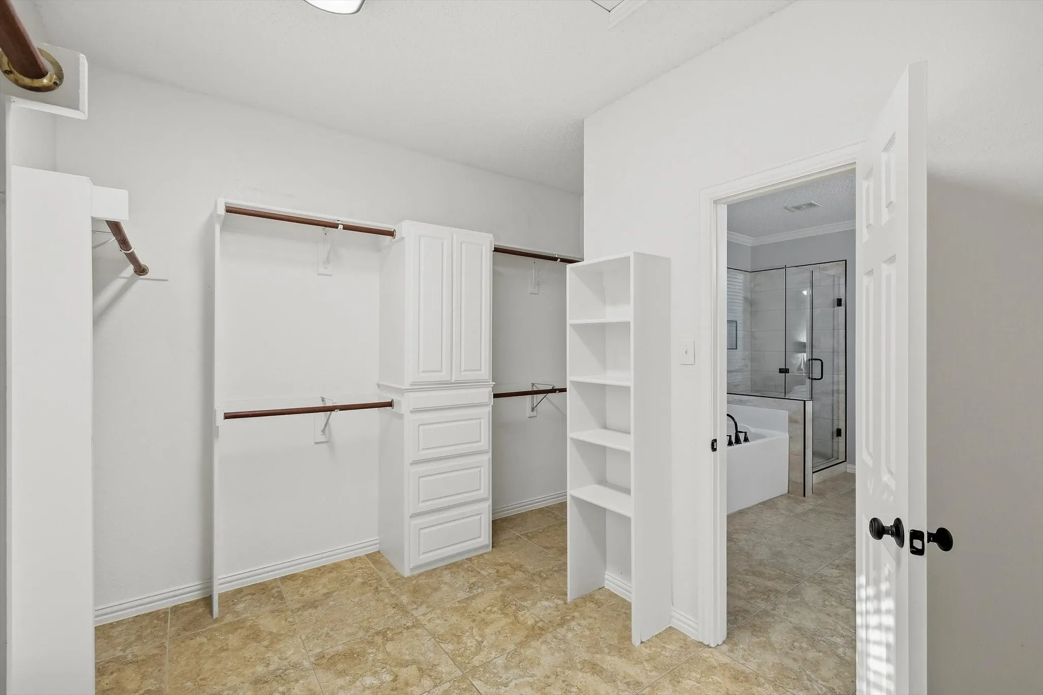 Expansive closet featuring built-in shelving, cabinet storage, and multiple hanging rods