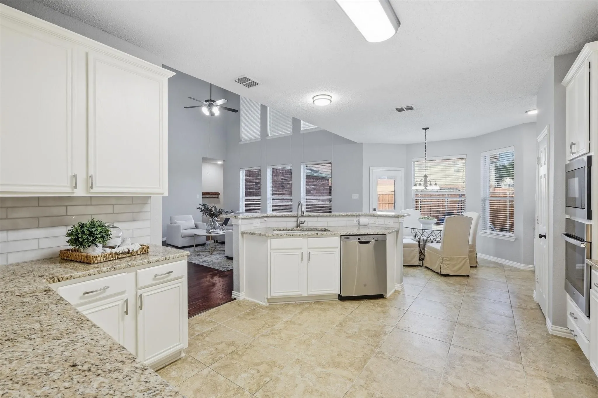 Kitchen featuring white cabinetry, granite countertops, an integrated dishwasher, built-in double ovens, and tile flooring