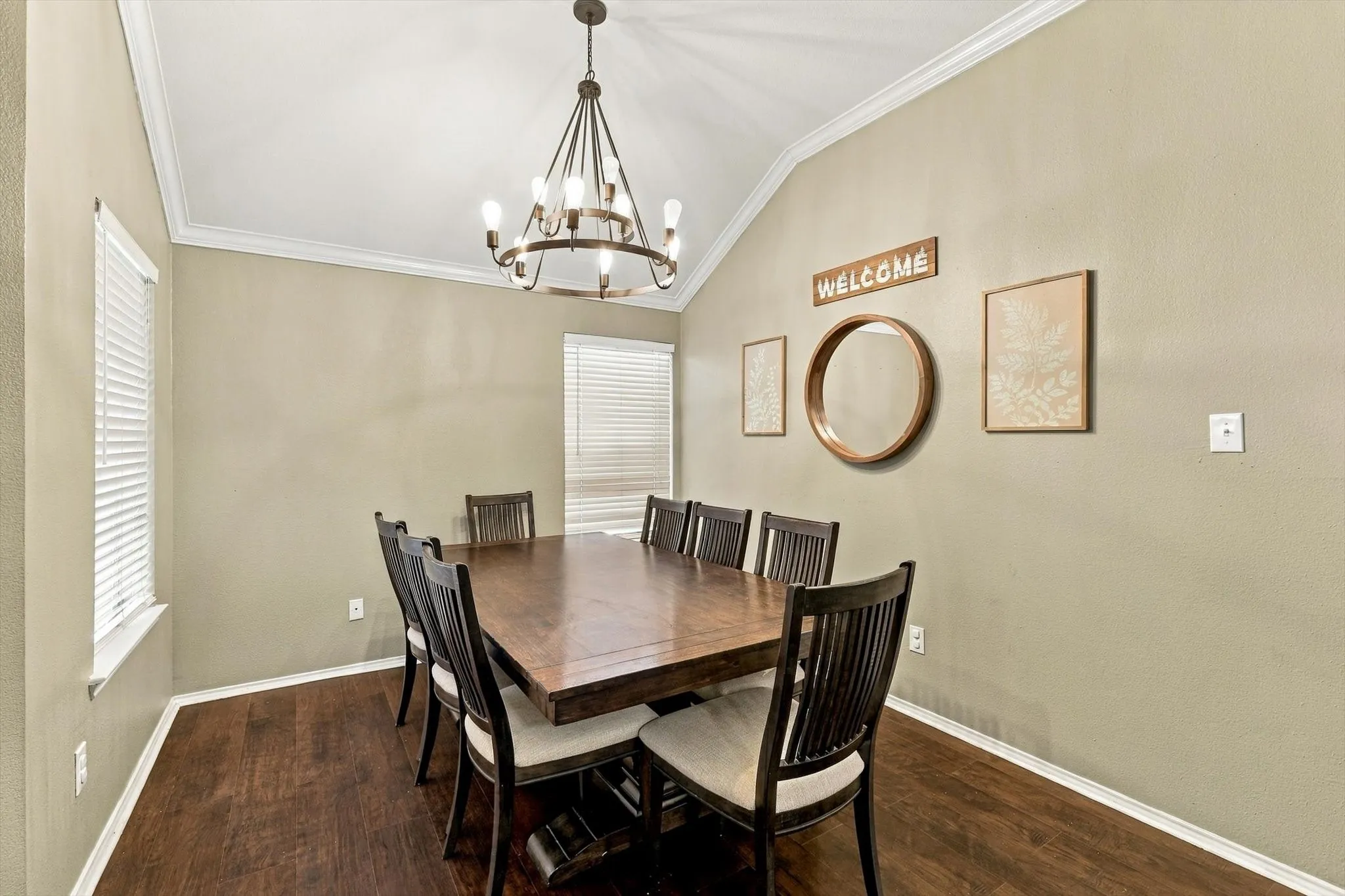 Vaulted ceiling with crown molding, wood-finish flooring, and a multi-arm chandelier
