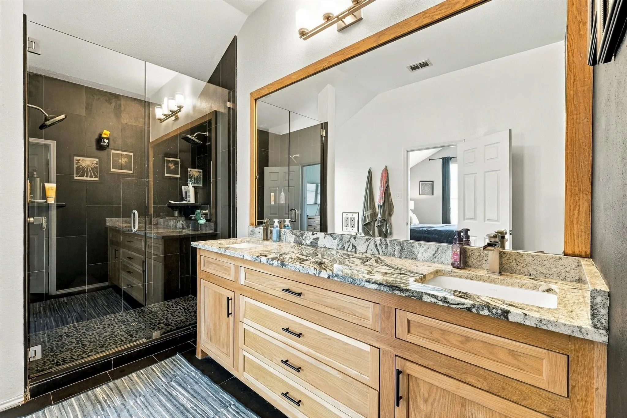 Dual vanity with wood-finish cabinetry and stone countertops