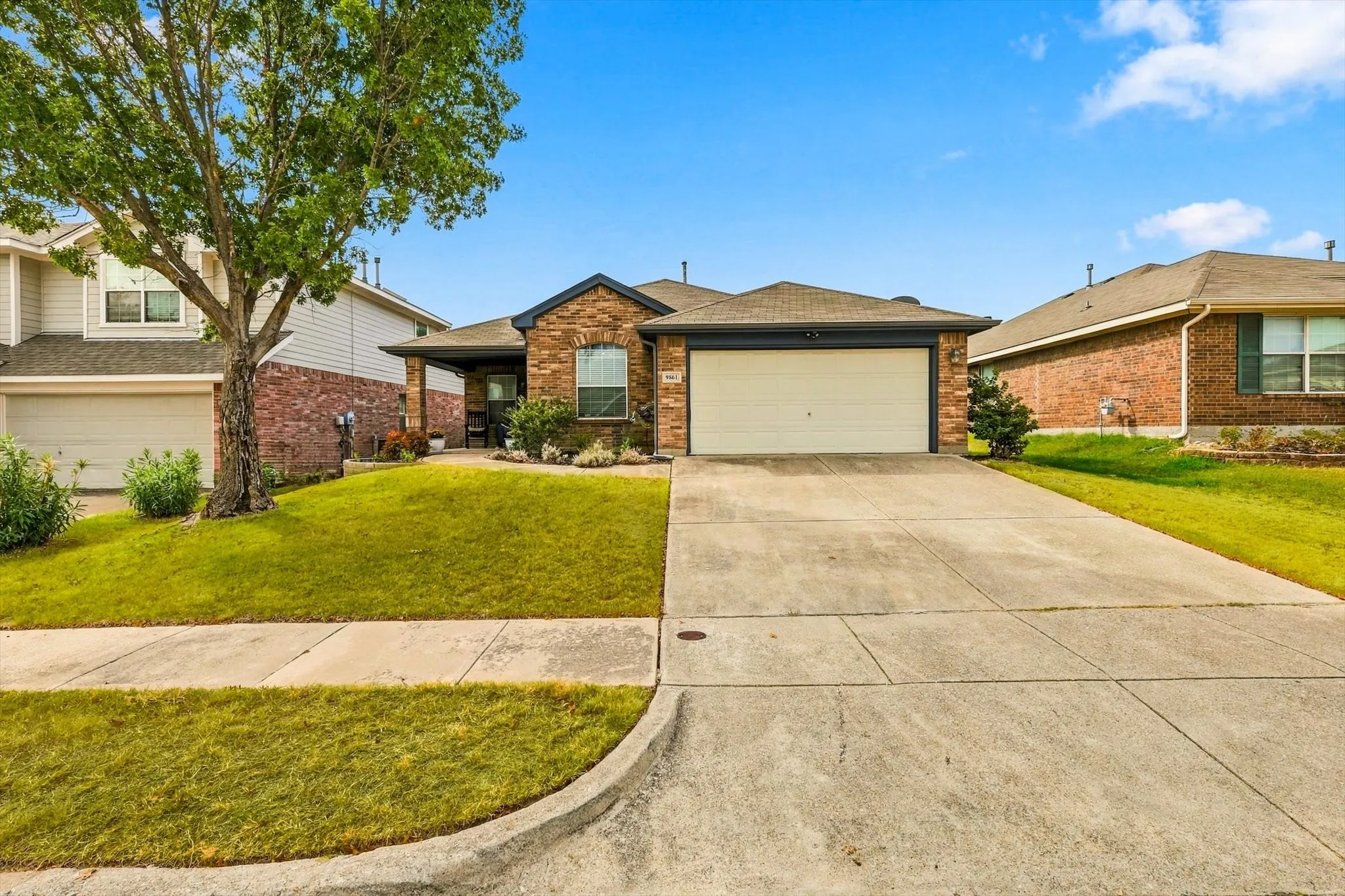 Brick exterior with stone accents, covered front entry, attached garage, and concrete driveway