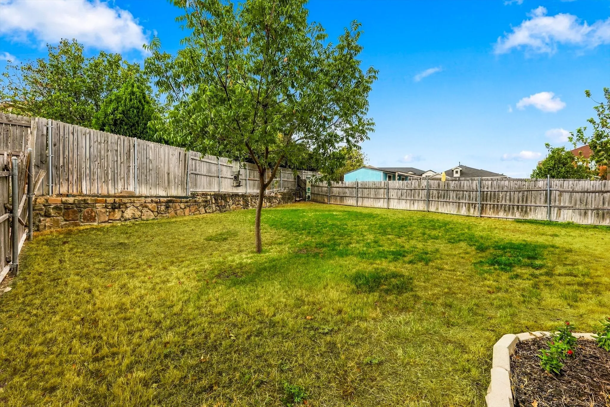 Expansive lawn area, perimeter fencing, and a mature tree
