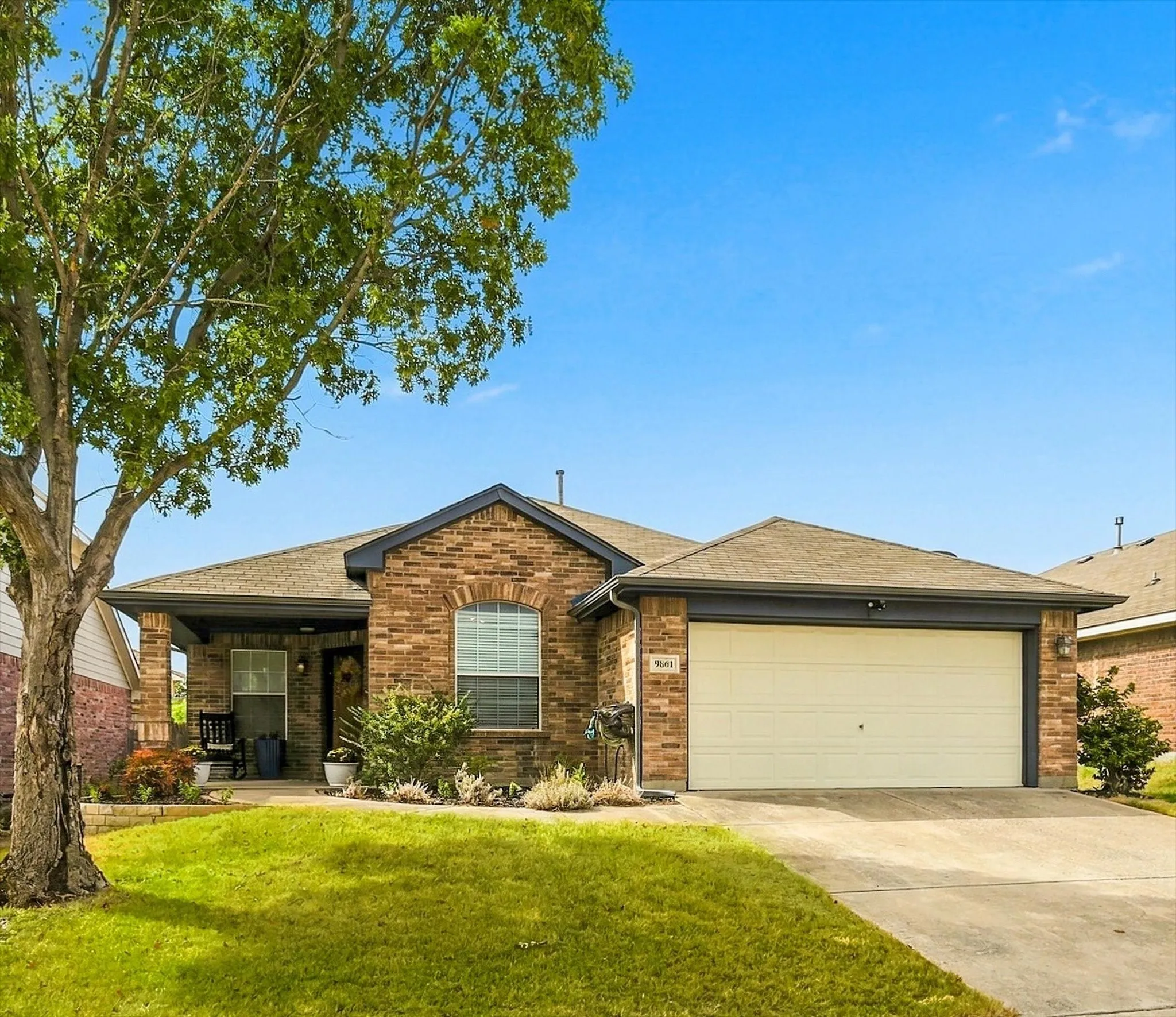 Brick exterior with a covered porch, arched window, and attached garage