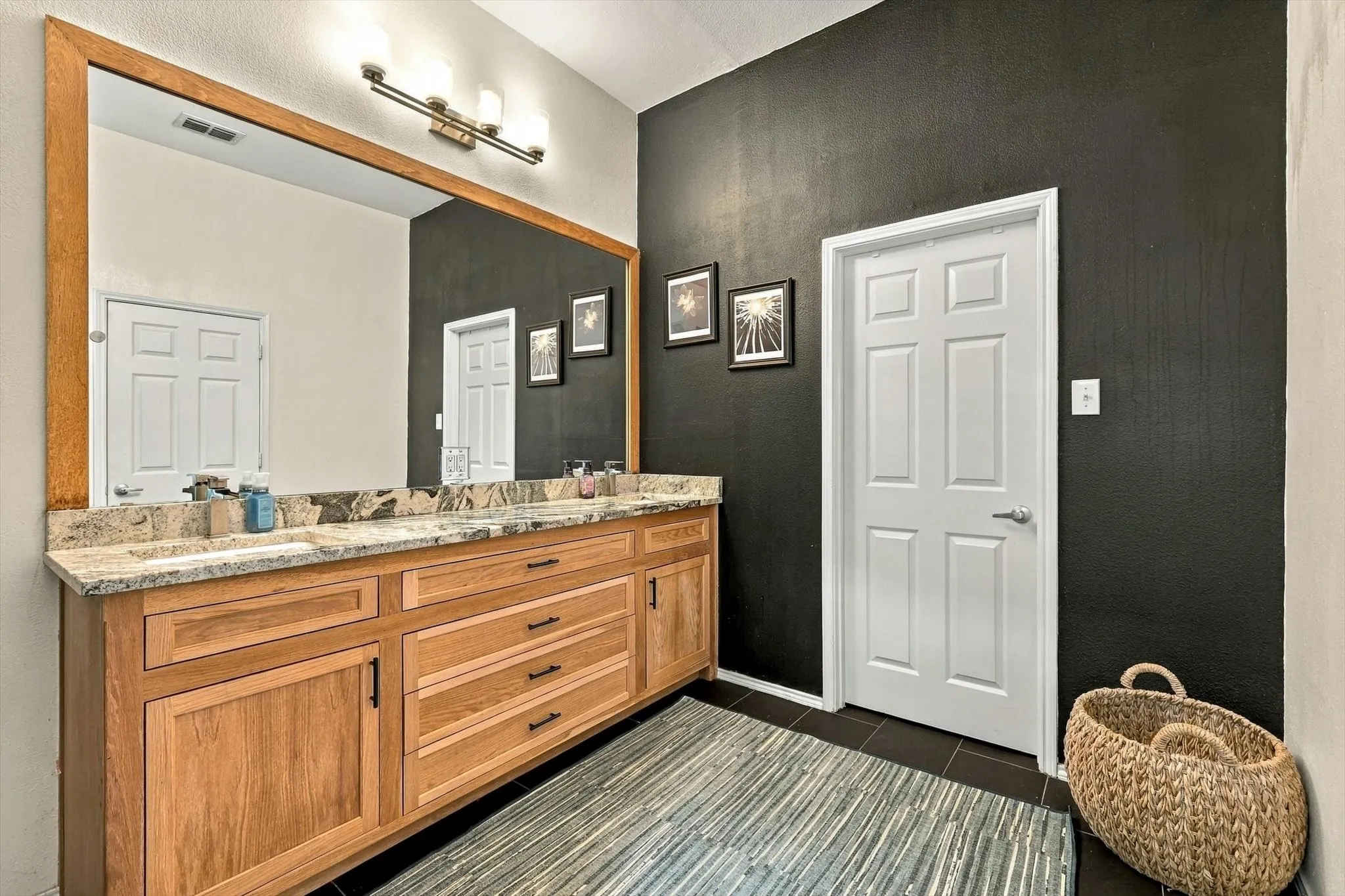Double vanity with wood-finish cabinetry, light-toned countertop, and dual undermount sinks