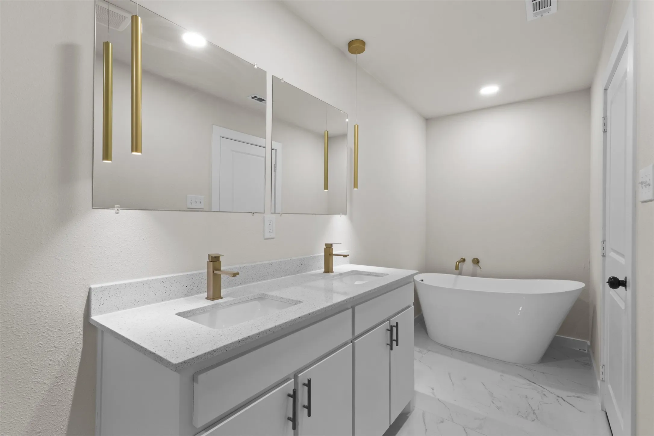 White dual vanity with integrated sinks, light-toned countertop, and gold-finish faucets