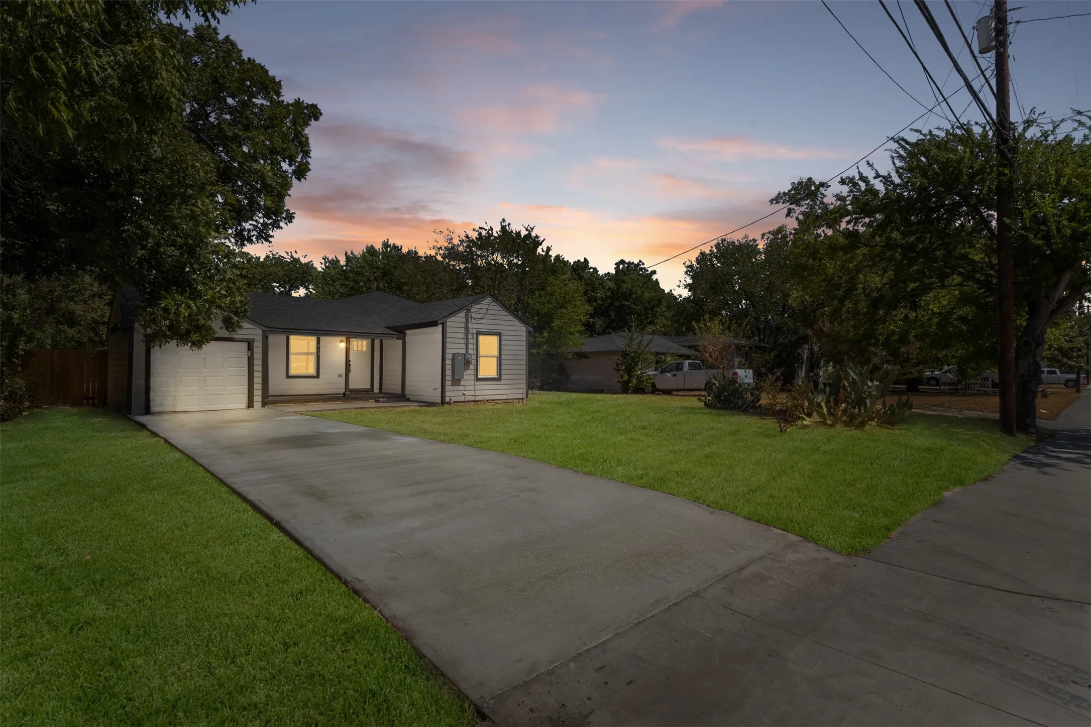 Exterior featuring a concrete driveway, attached garage, and established landscaping