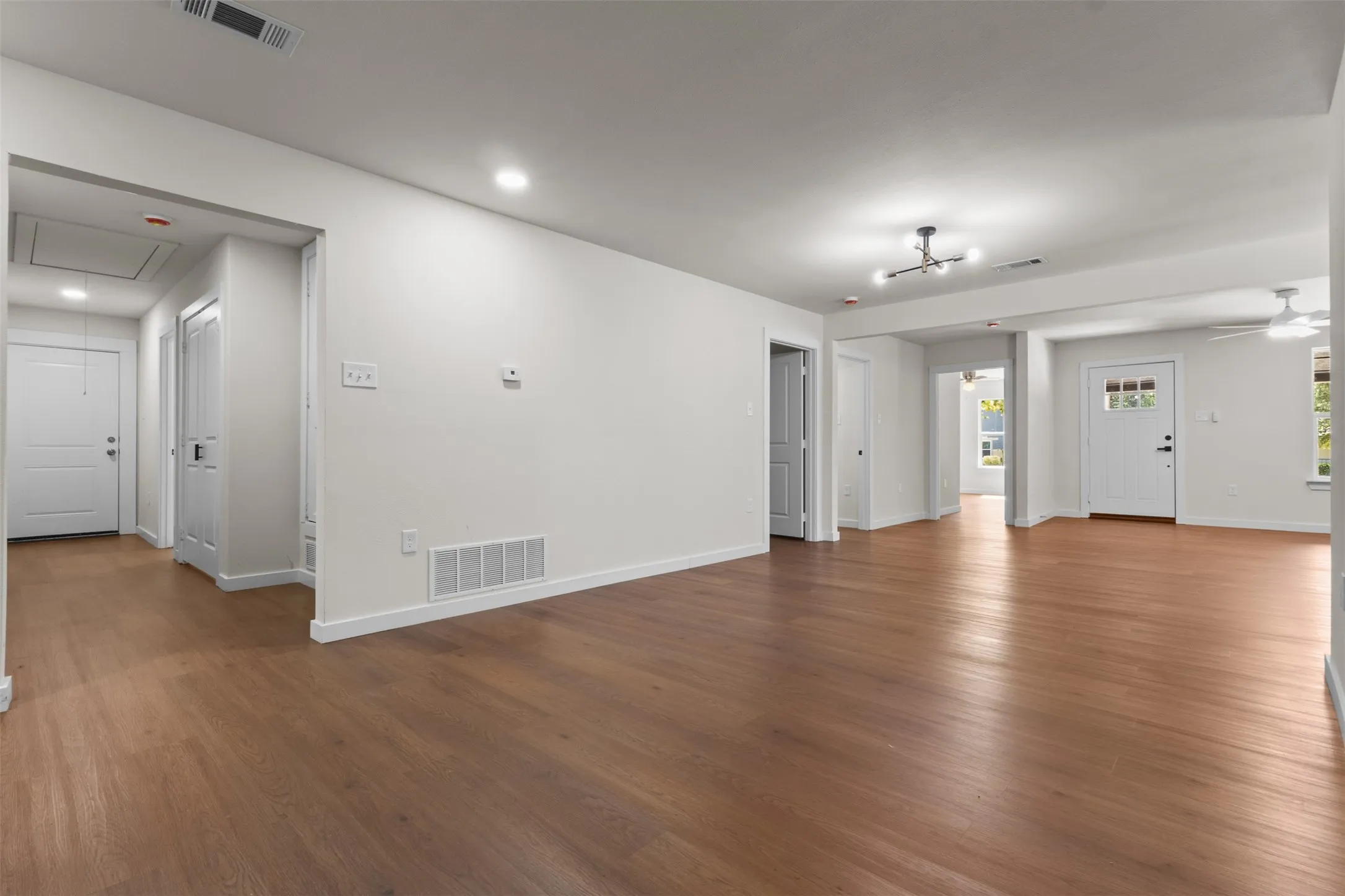 Expansive open-concept living area with wood-finish flooring, recessed lighting, and a modern ceiling fixture
