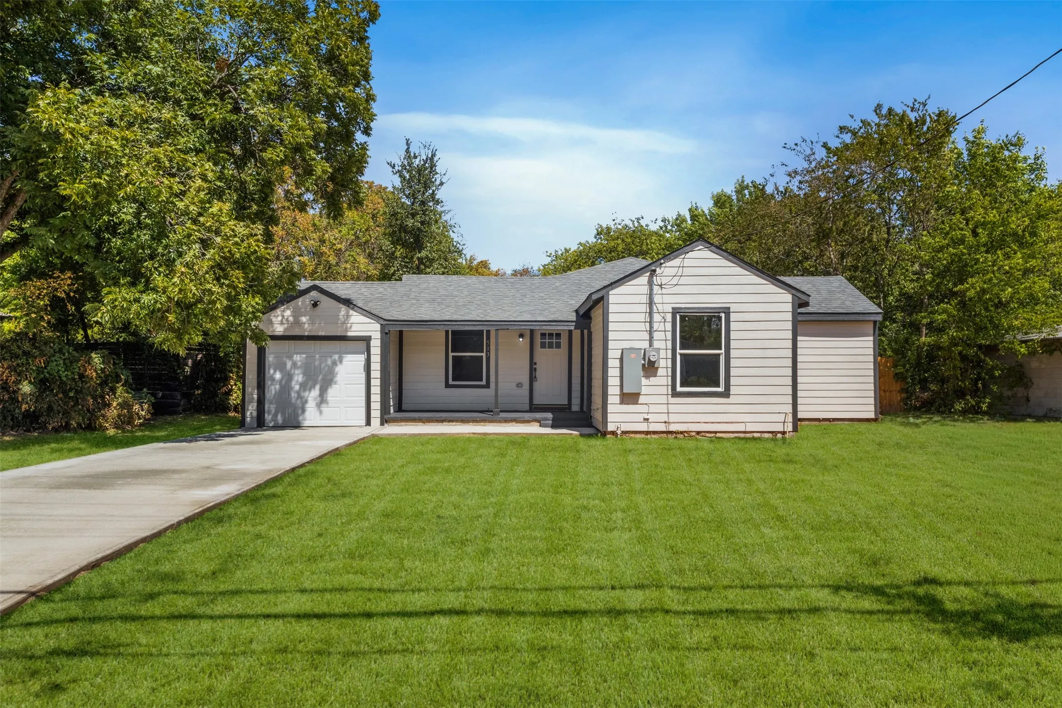 Exterior featuring a light-colored siding, a dark roof, a single-car garage, and a concrete driveway