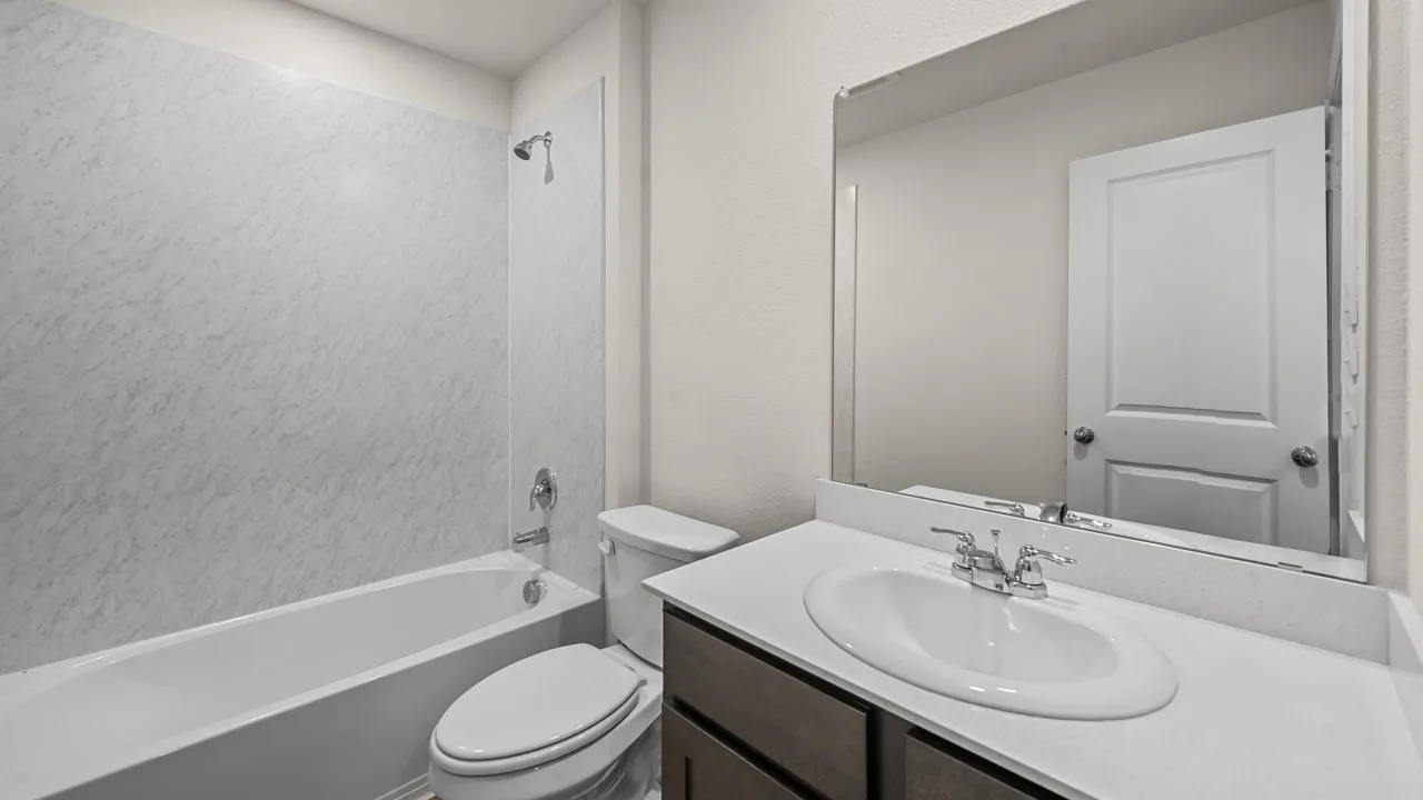 Bathtub with shower, toilet, vanity with integrated sink, and wall-mounted mirror