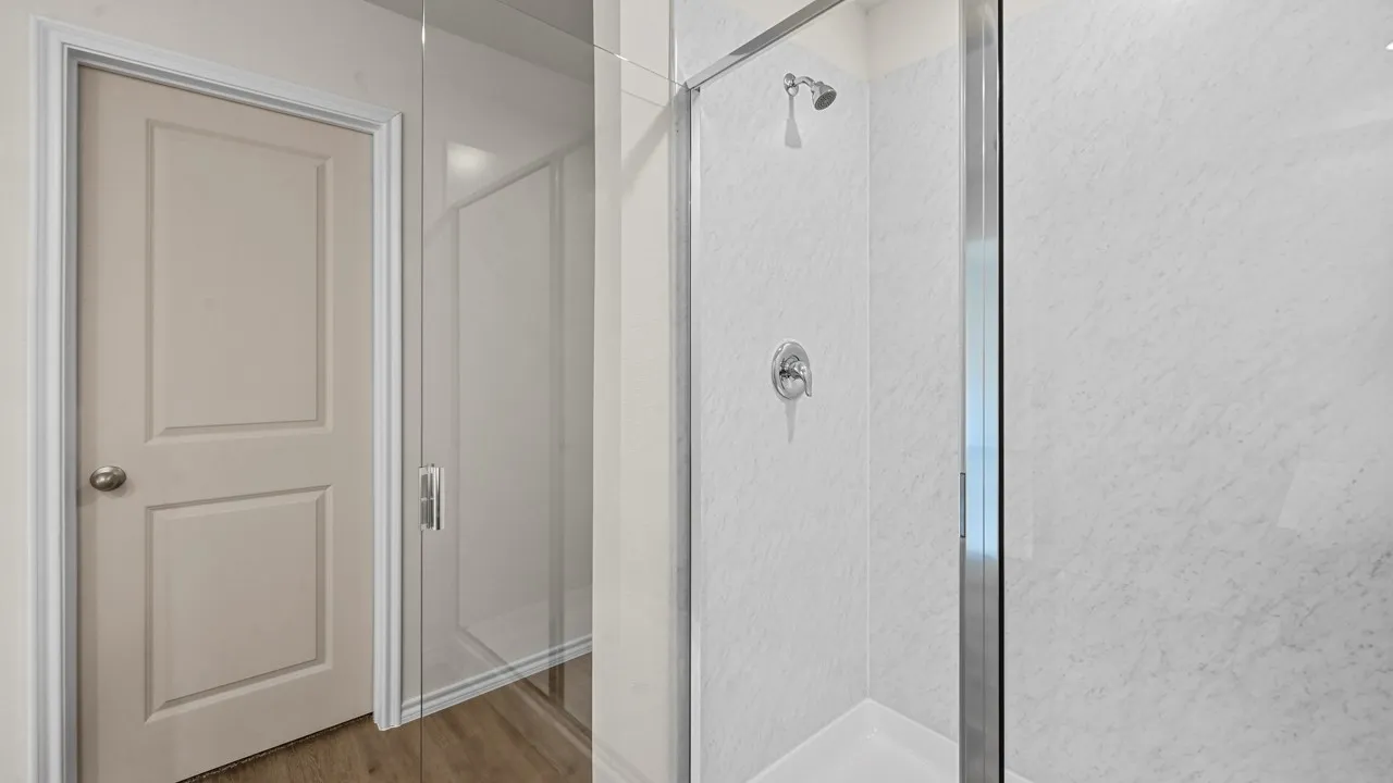 Shower enclosure with clear glass paneling, white shower base, and white textured wall panels