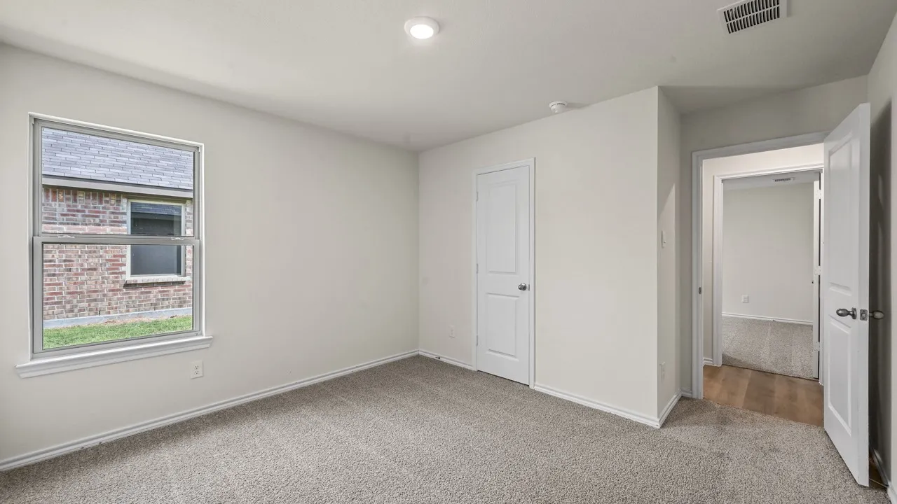 Neutral wall paint, recessed ceiling lighting, textured carpeting, white trim, and a window with exterior brick detail