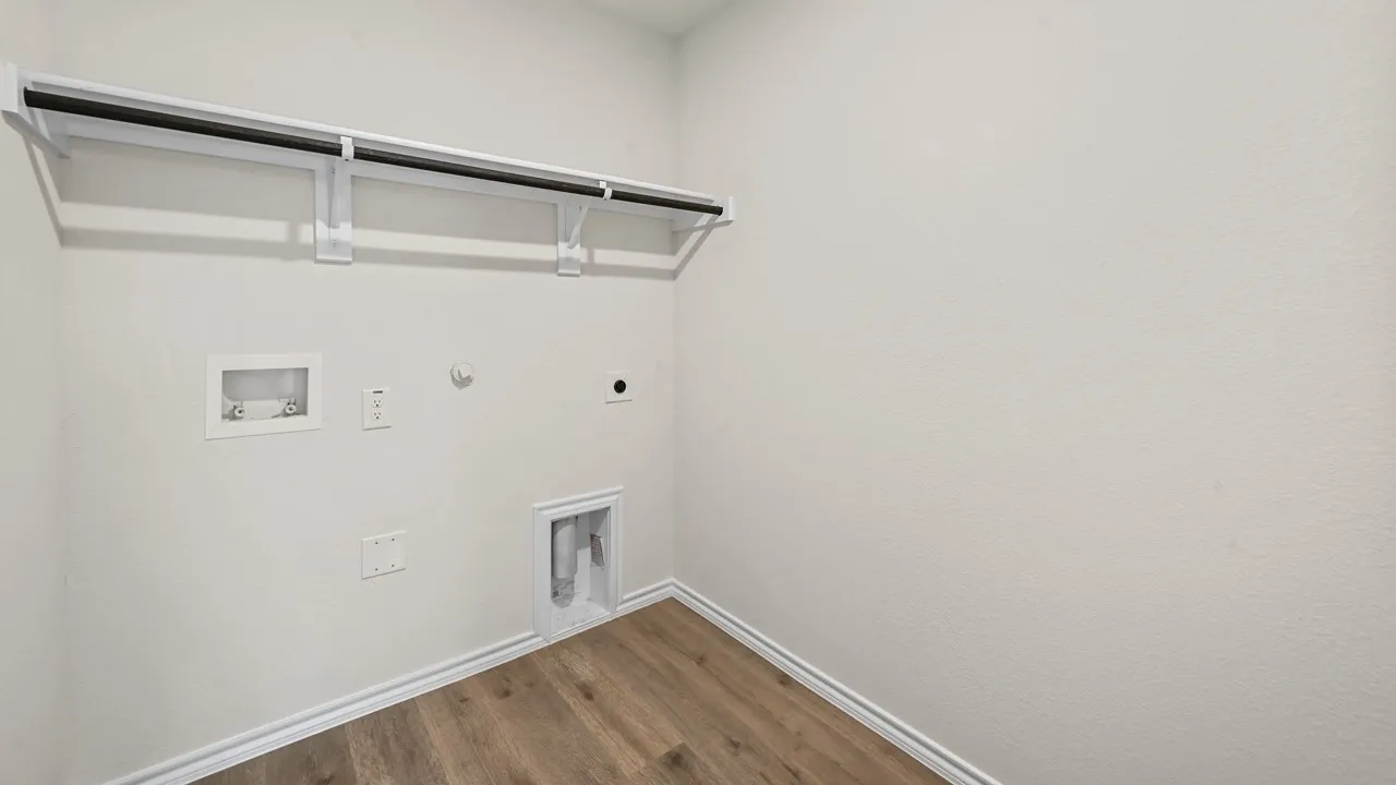 Laundry area featuring wood-finish flooring, white walls, and a built-in hanging rod