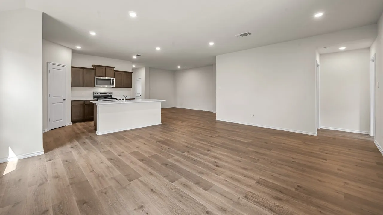 Open-concept living space featuring wood-finish flooring, recessed lighting, and a kitchen island with a sink