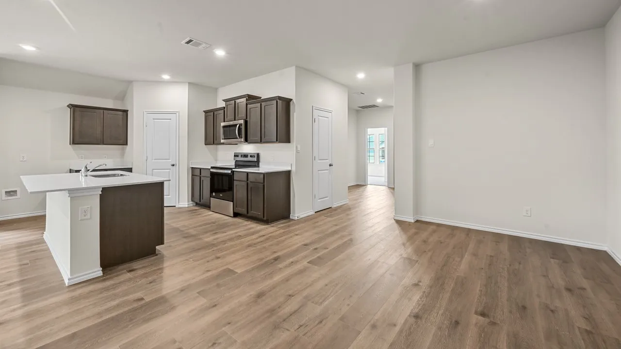 Wood-finish flooring throughout, kitchen island with a light-toned countertop, dark wood-tone cabinetry, stainless steel range, and recessed lighting
