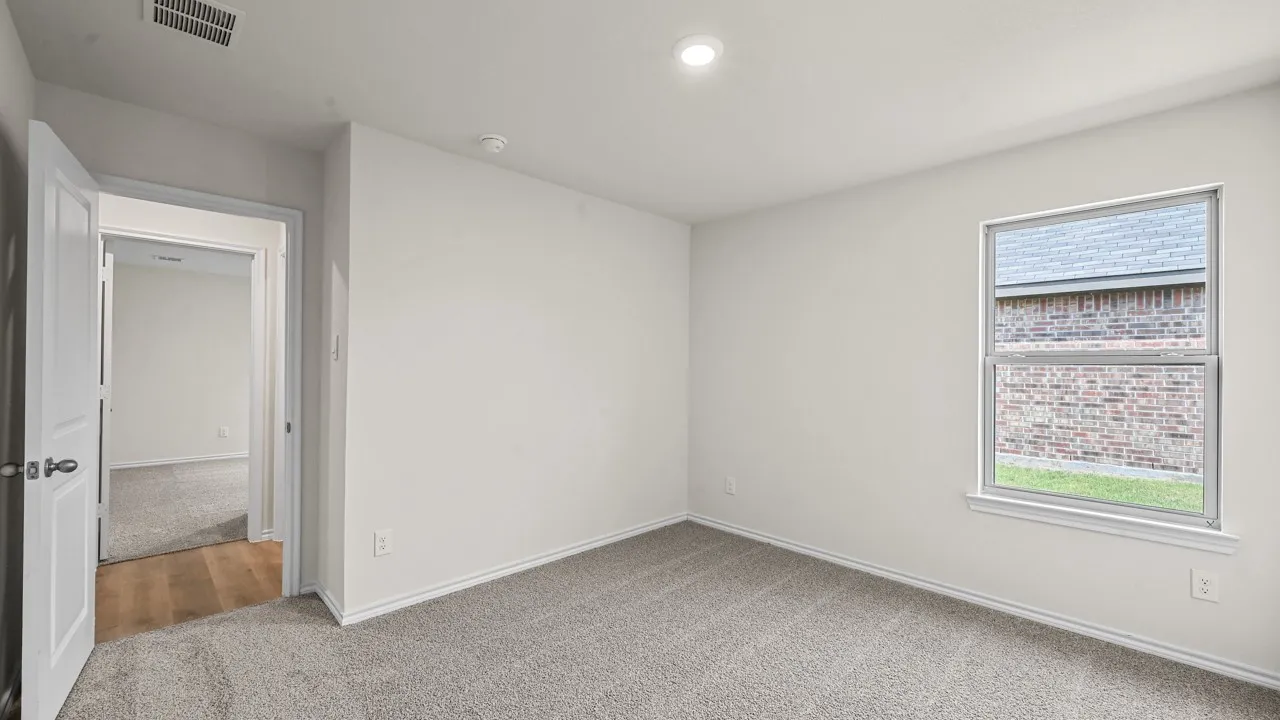 Recessed ceiling lighting, light-colored walls, carpeted flooring, wood-finish flooring in doorway, window with exterior brick detail