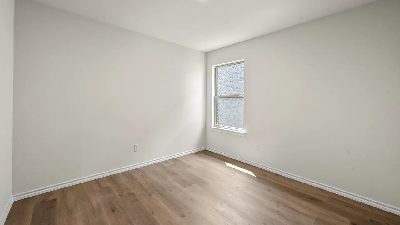 Wood-finish flooring with white trim and a single window